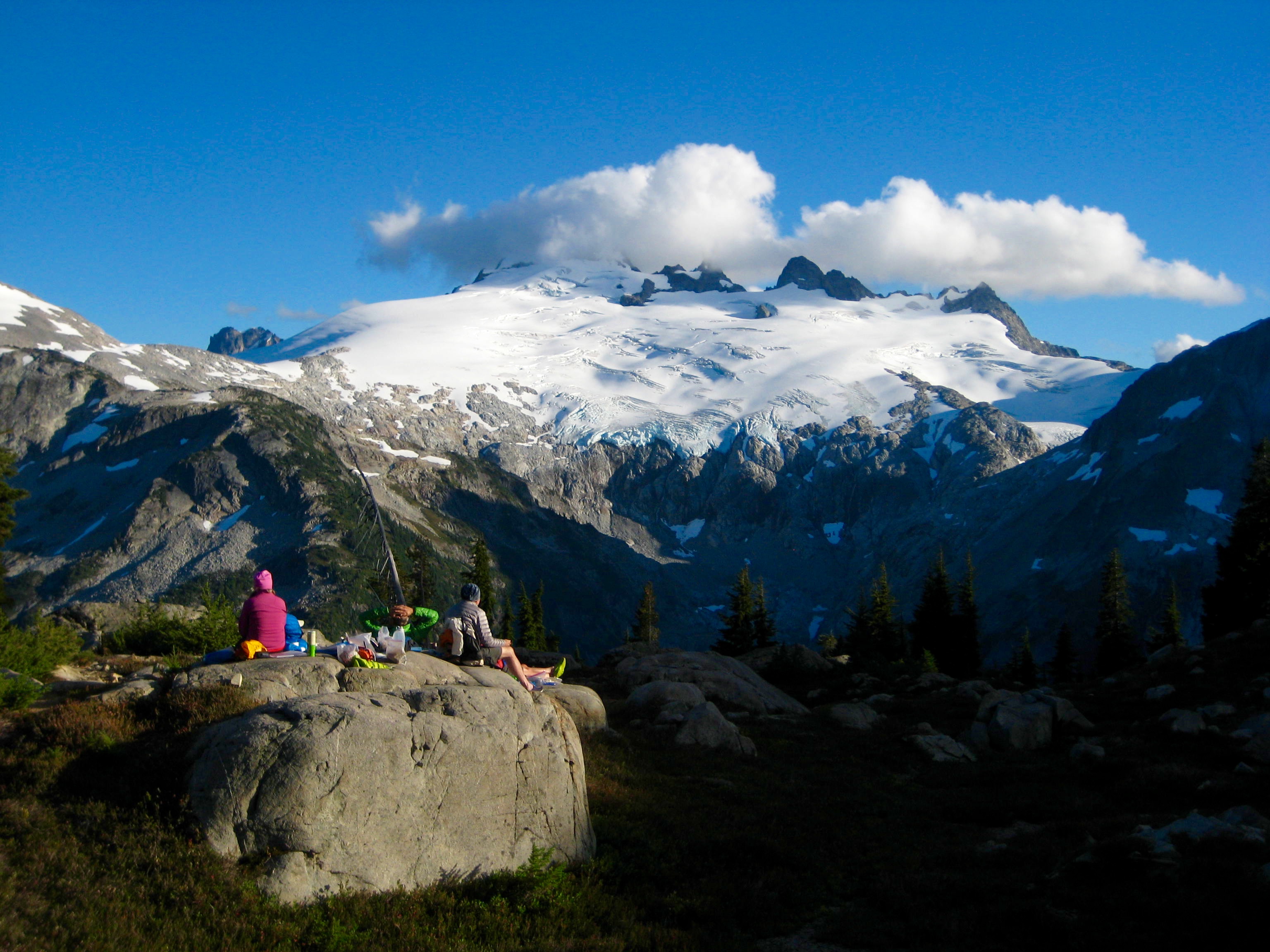 mountain climbers relaxing on a large boulder on the Middle Lakes plateau with Mt Challenger in the background