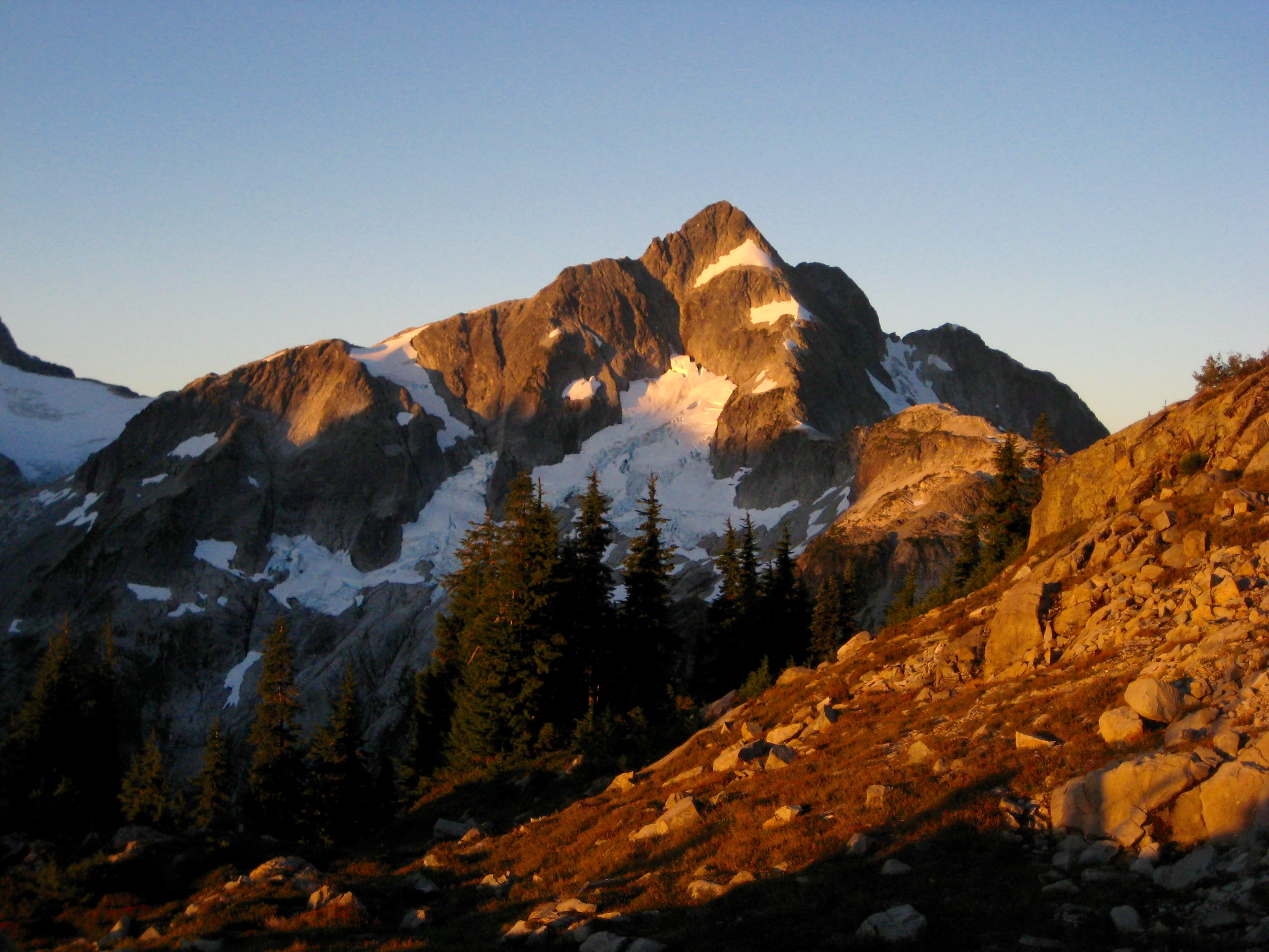 Sunlight of Wahtcom Peak with linguring snow patches as seen from Middle Lake Plateau in the American Chilliwack Mountains