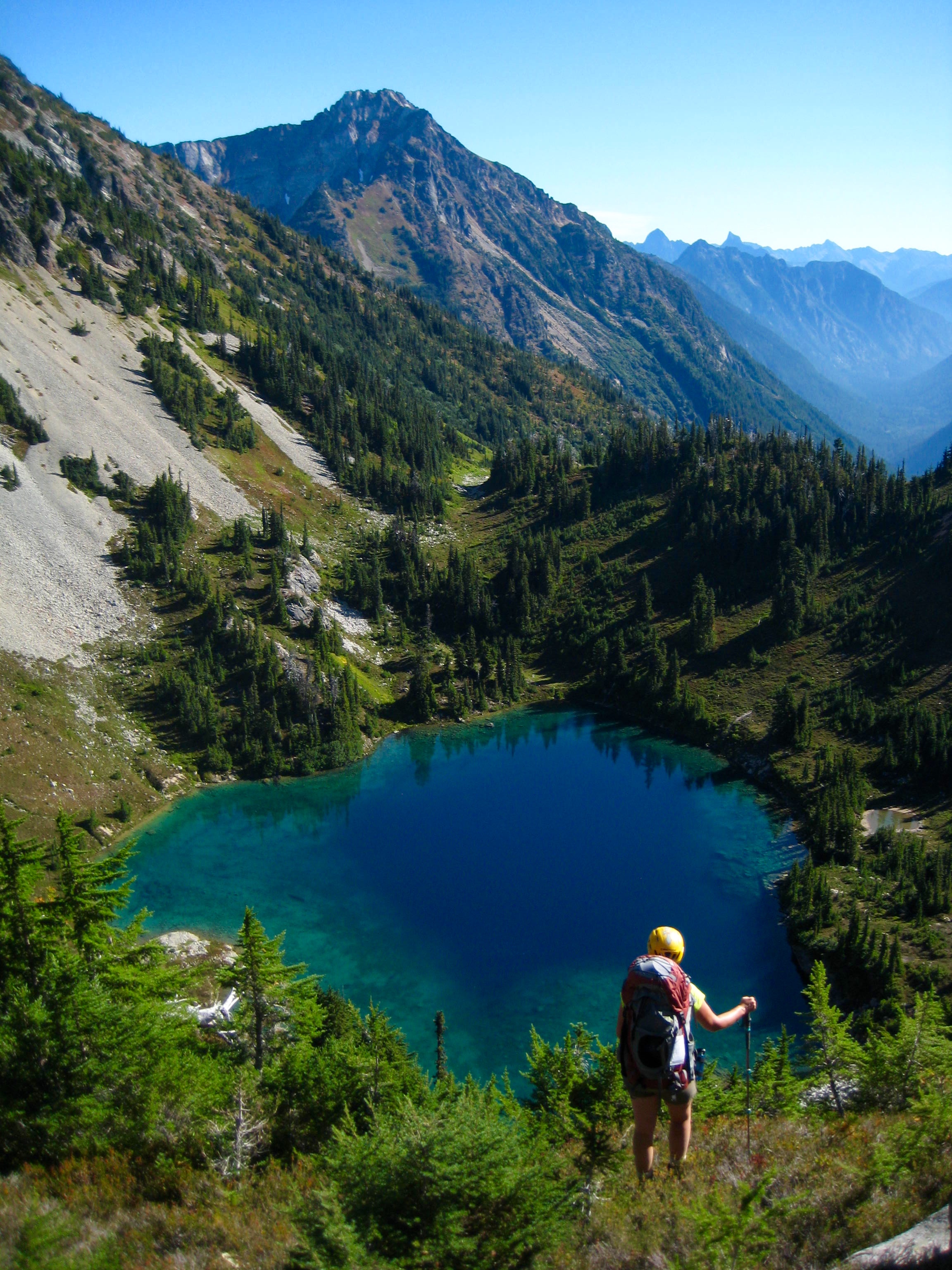 mountain climber dropping through greenary into East Lake in the American Chilliwack Mountains