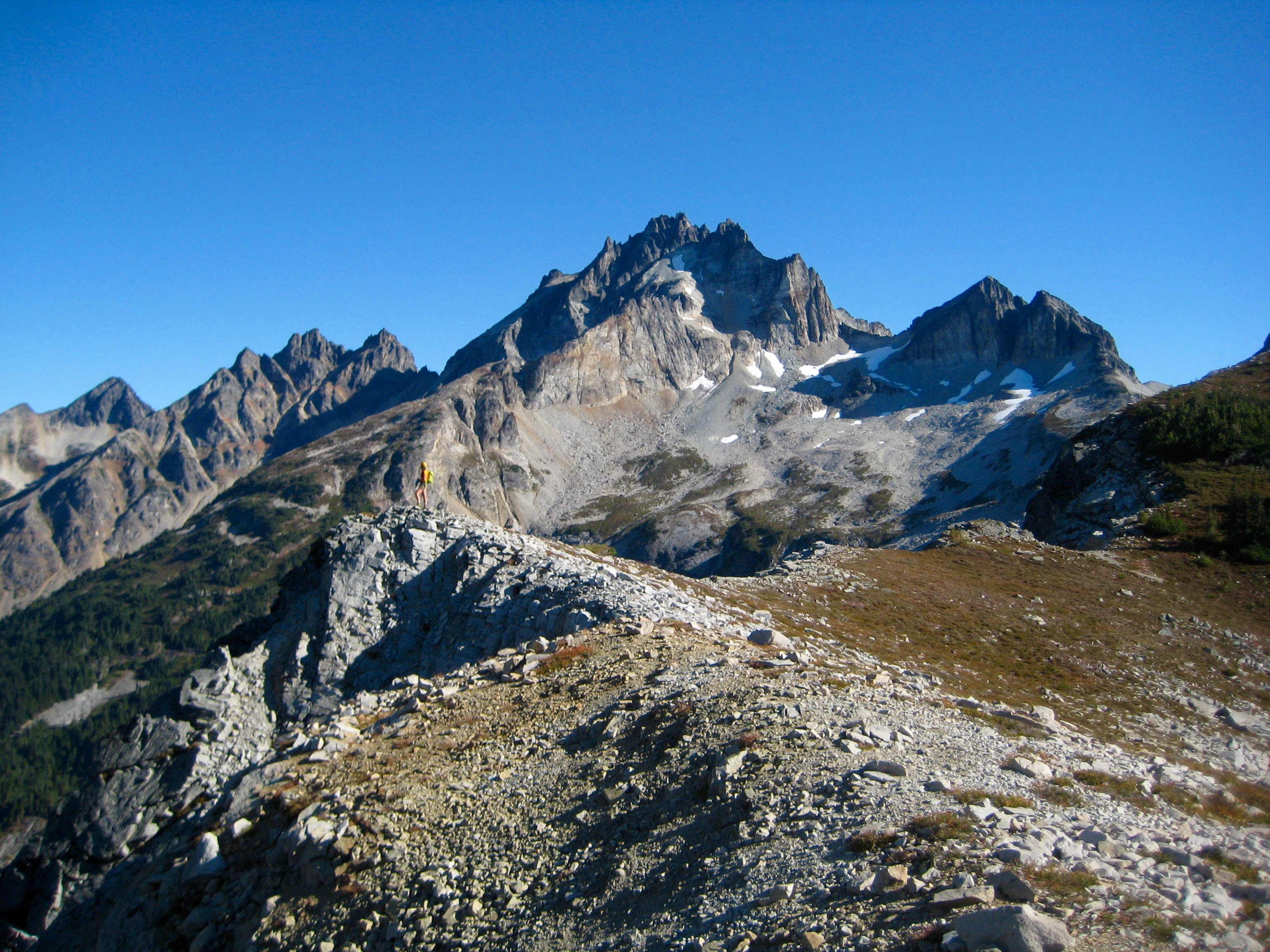 mountain climber and rocky Mt Redoubt in the American Chilliwack Mountains as seen from Indian-Bear Saddle