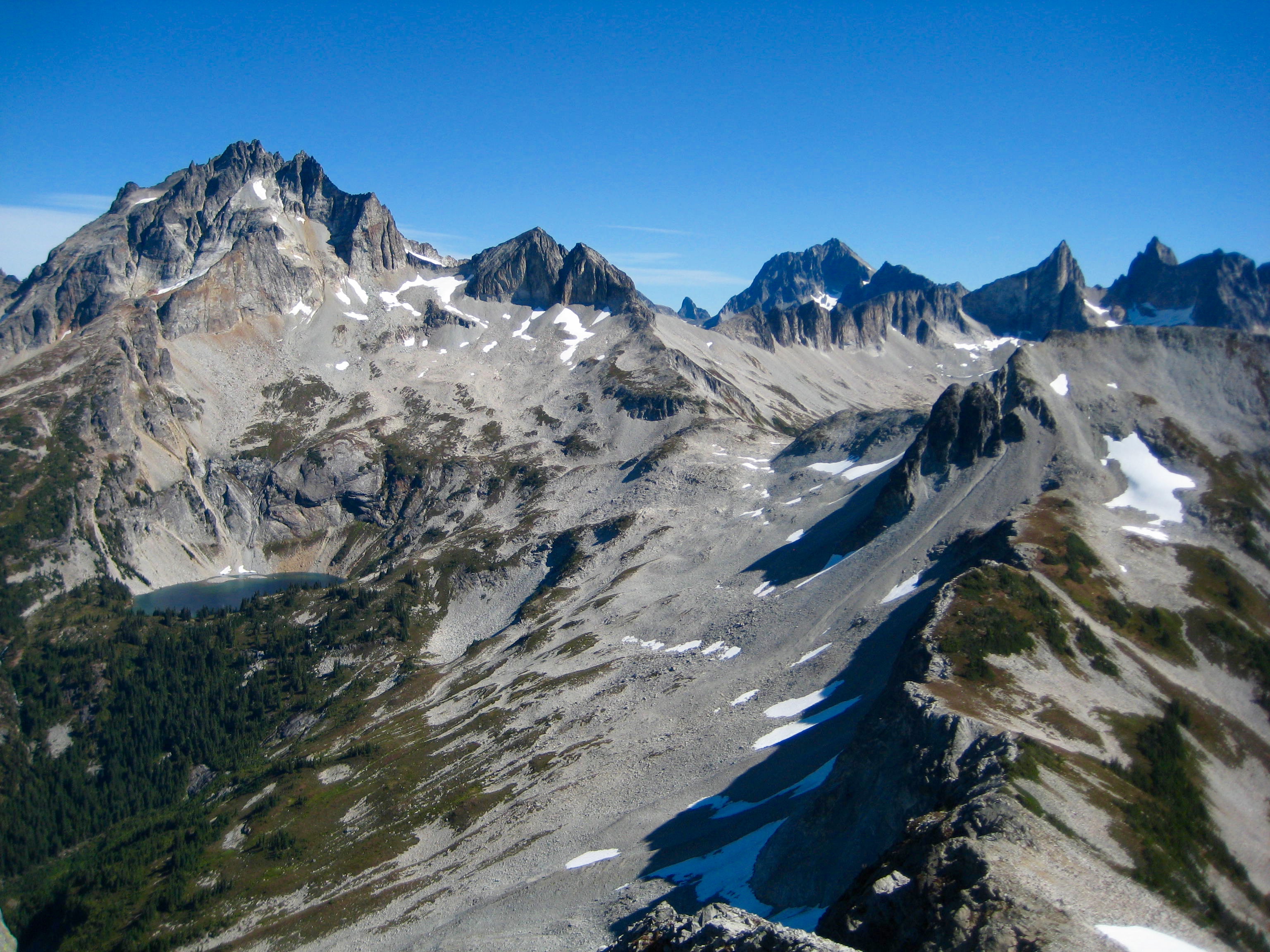 Mt Redoubt and the Mox Peaks with linguring snow patches from Bear Mountain East ridge in the American Chilliwack Mountains