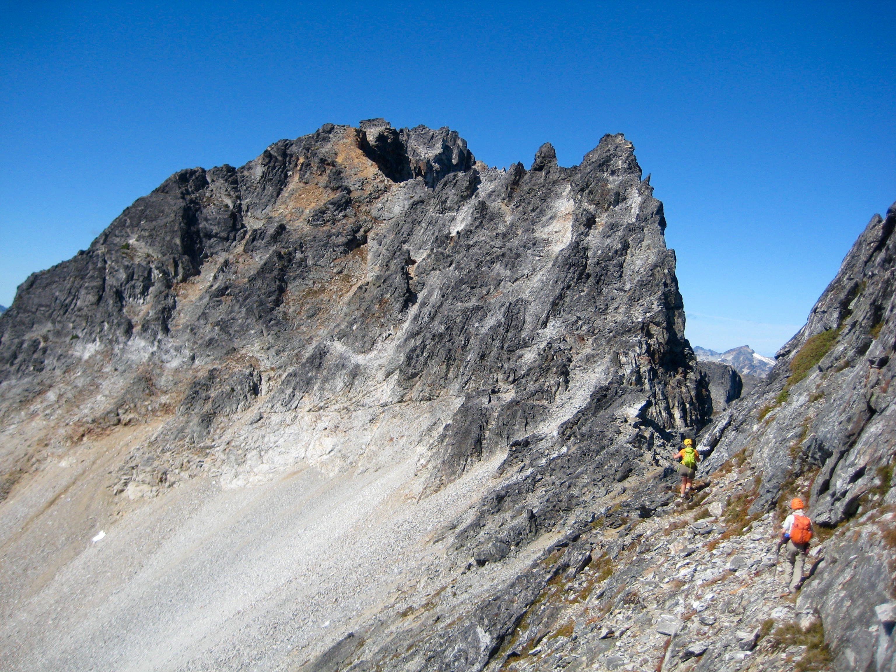 mountain climbers traversing rock ledges heading toward Bear Mountain summit ridge in the American Chilliwack Mountains