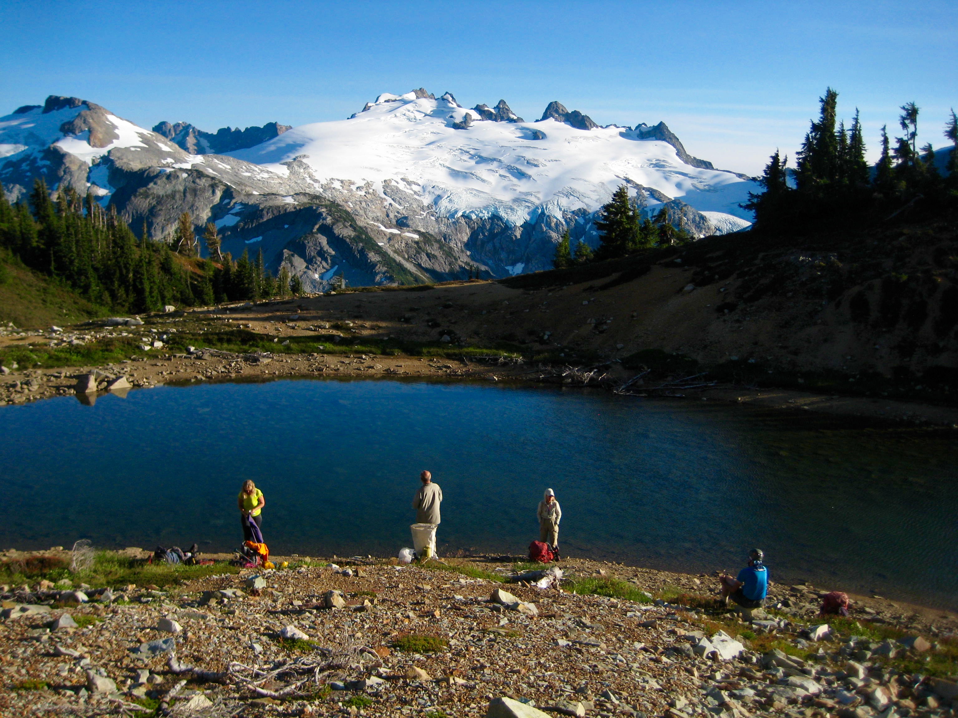 mountain climbers taking a break at Tiny Lake with Mt Challenger of the Southern Pickets 