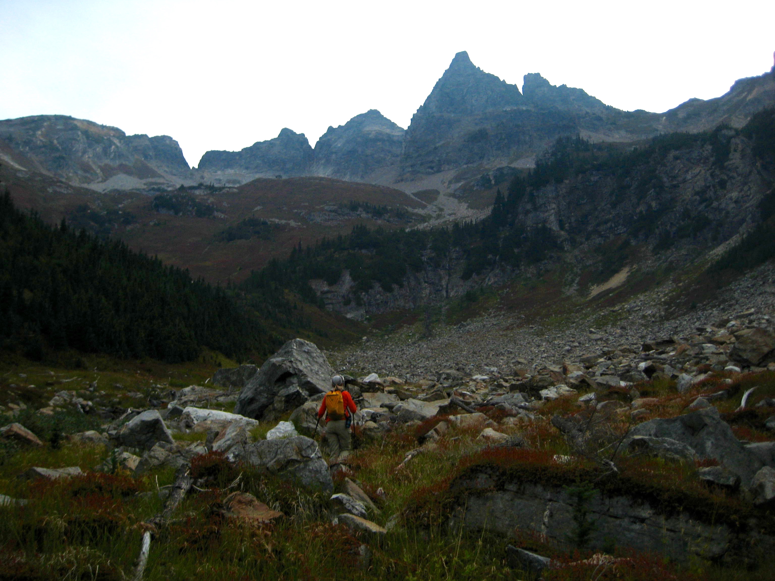 mountain climber hiking through west Sitting Bull basin with the summit of Sitting Bull Mountain in the background