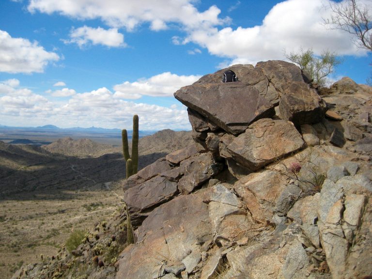 Rocks and cactuses and puffy clouds are seen from Valley Vista Viewpoint during Turnbuckle Trail Traverse