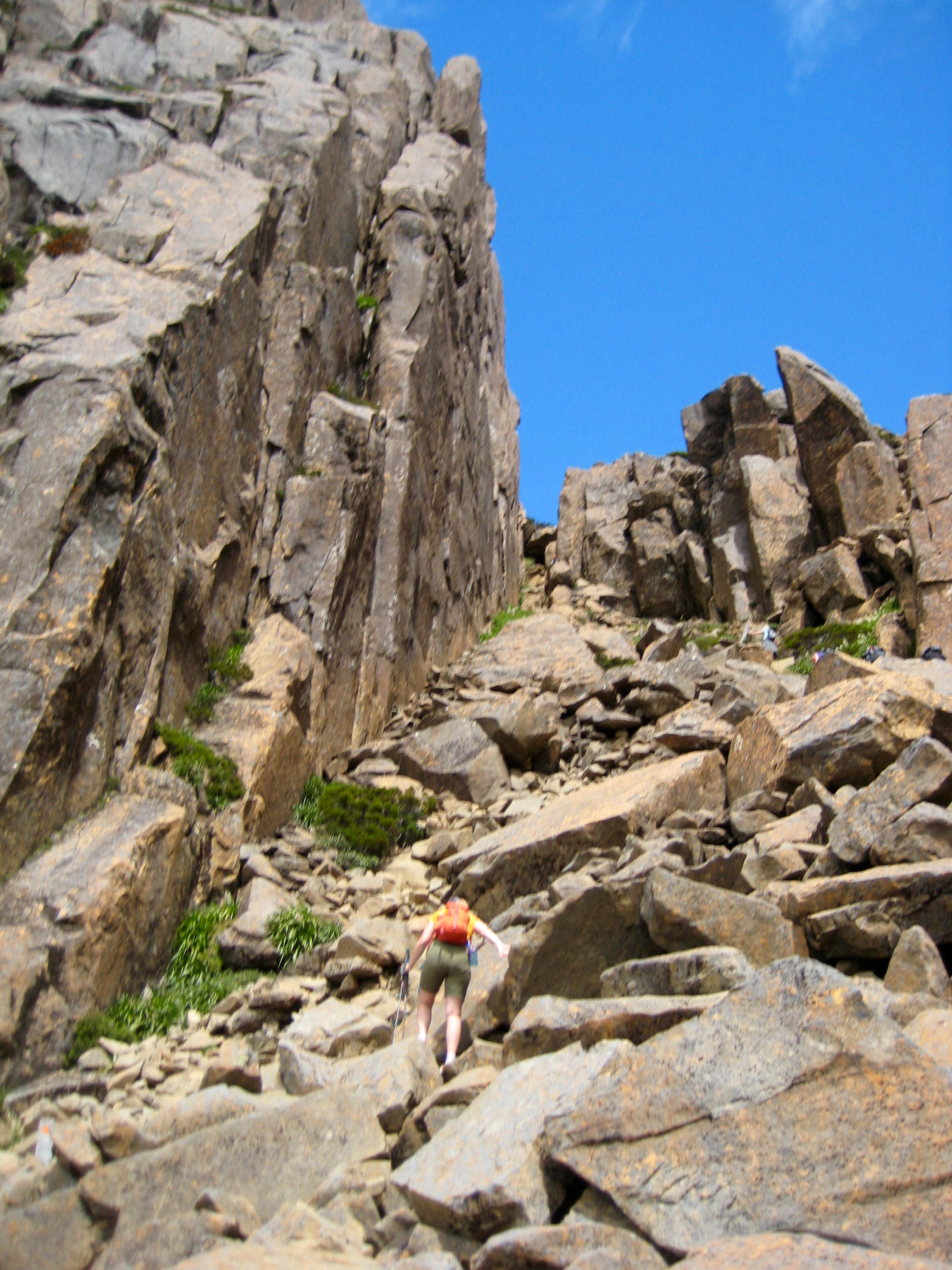 hiker scrambling rock towards the summit of Mt Ossa on the Overland Track