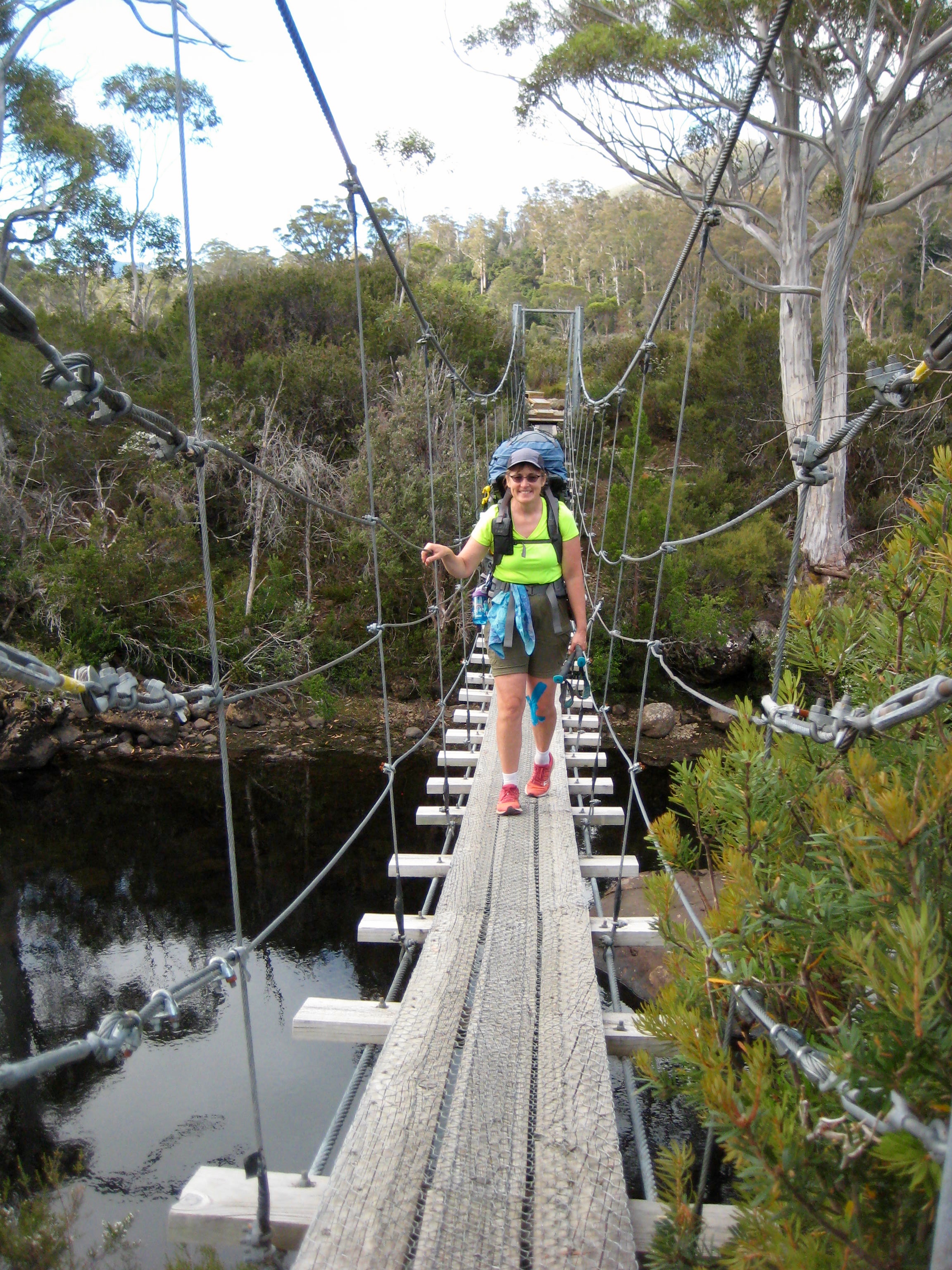 Trekker crossing suspension bridge over Narcissus River