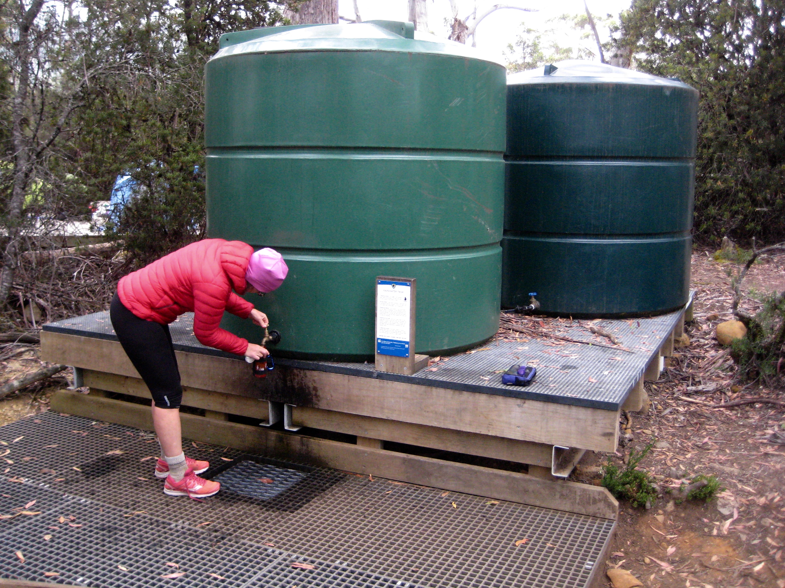 Filling Water Bottles From Rain Barrels At Narcissus Hut
