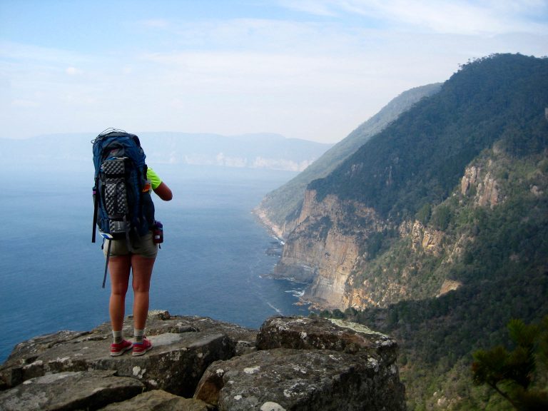 Trekker standing on the cliffs end looking at Cape Hauy on the Three Capes Track in Tasmania