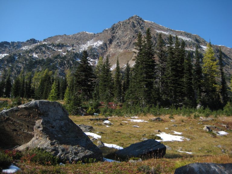 rocky Deadhorse Peak stands behind a large grassy meadow during the Deadhorse Traverse in the Chilliwack Mountains
