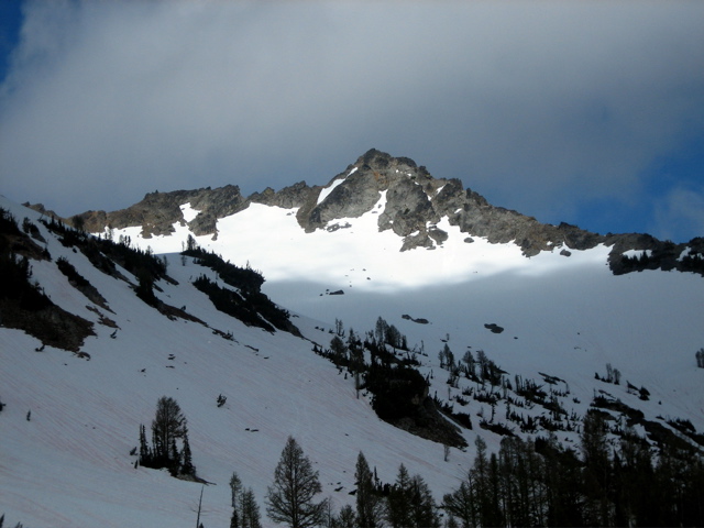 Sunlight hits the summit of Chilly Peak above a snow bowl