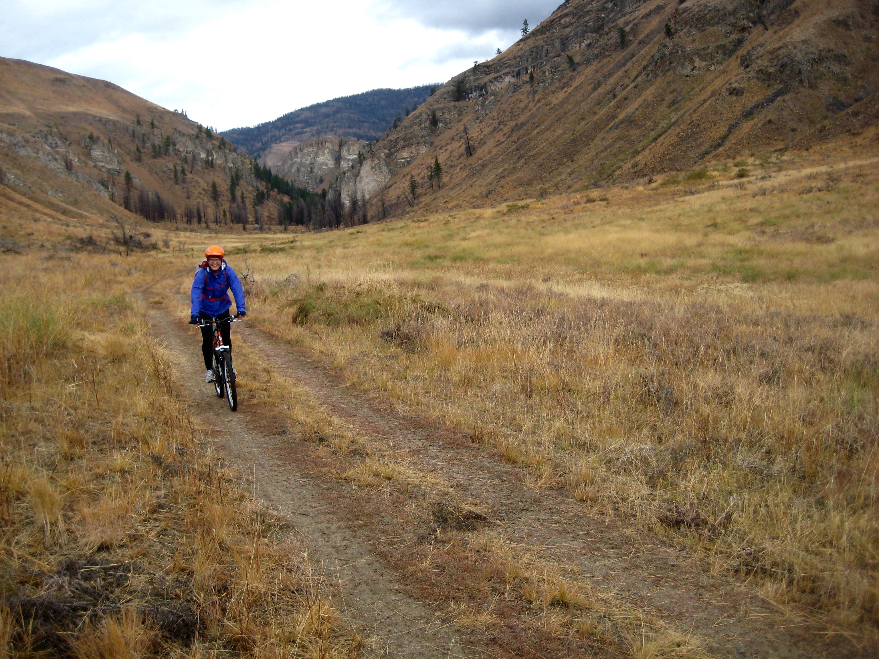 A mountain biker cruises through wheatfields of the Pipestone Canyon Bike Loop