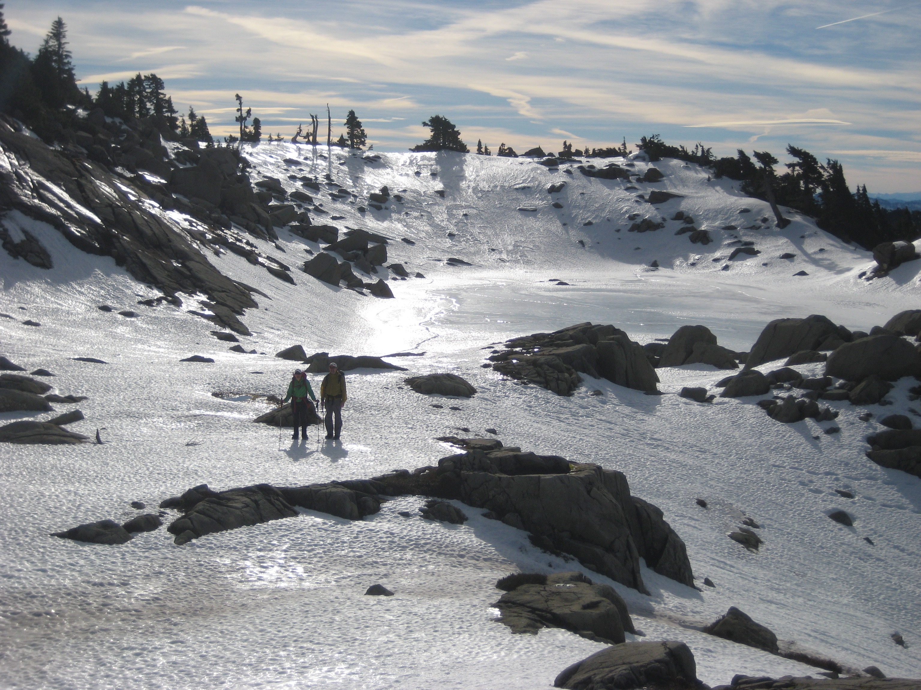Two mountain climbers ascend snow slopes on Mt Persis above a frozen lake