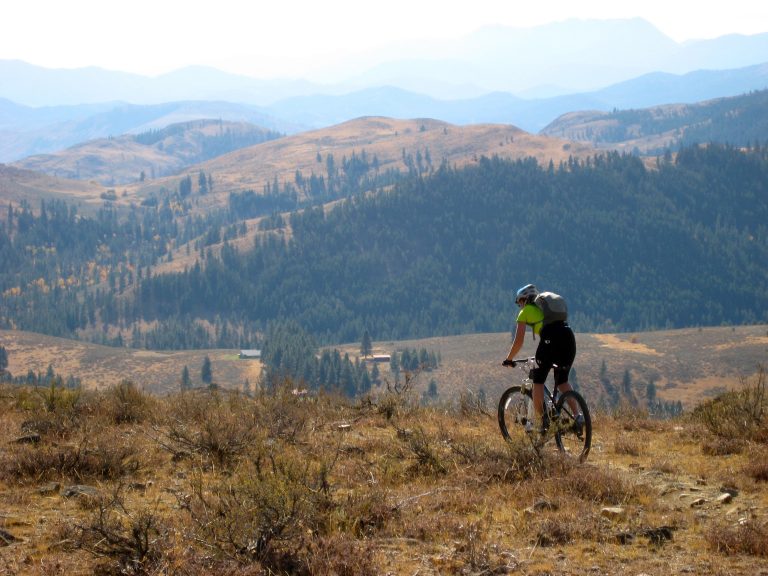 A mountain biker descends an arid ridge crest on Buck Mountain Bike Loop