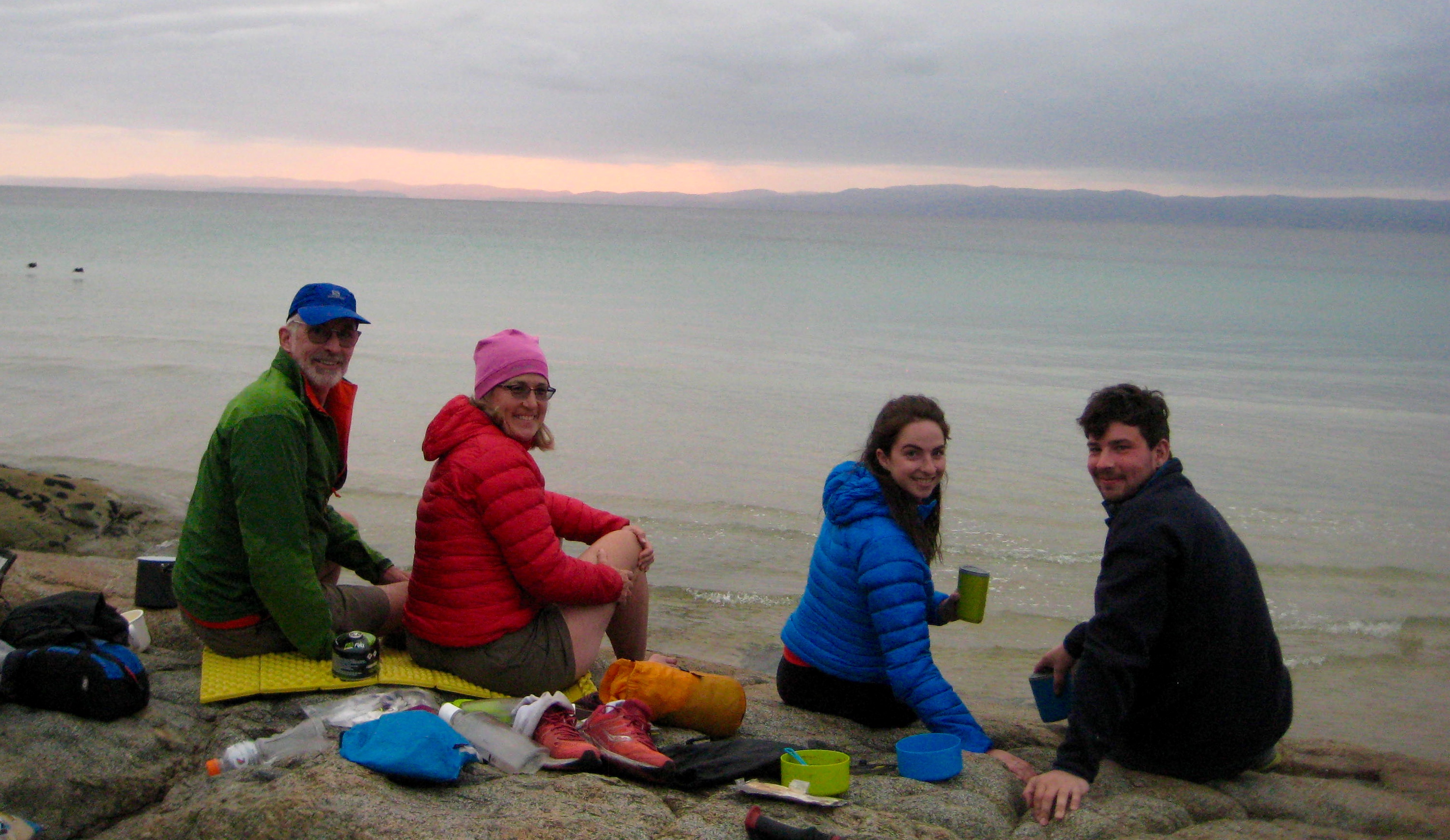 hikers having dinner on the rock slabs at Hazards Beach in Tasmania's Freycinet National Park with the ocean in the background