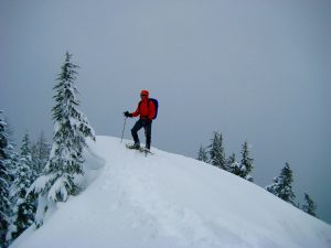 A snowshoer stands atop the snow-capped summit of Mt Catherine in the Cedar-Green Mountains