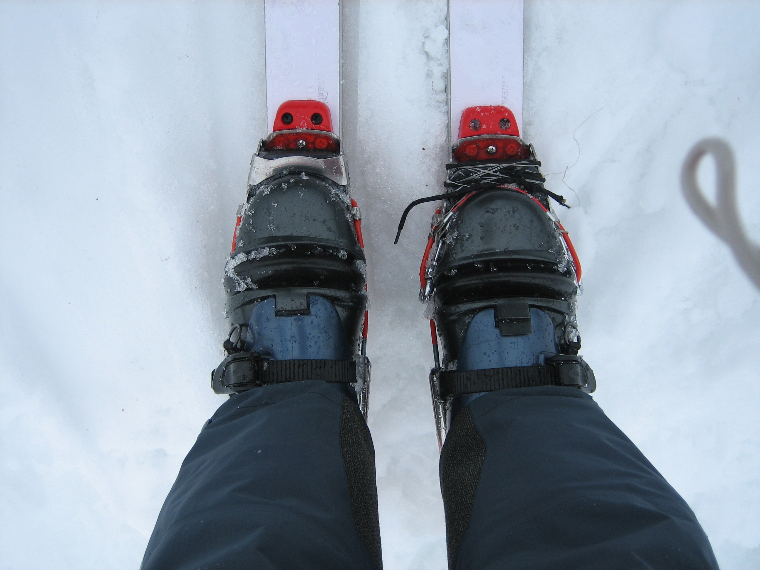 The boots of a backcountry skier are attached to a damaged binding on Suiattle Mtn