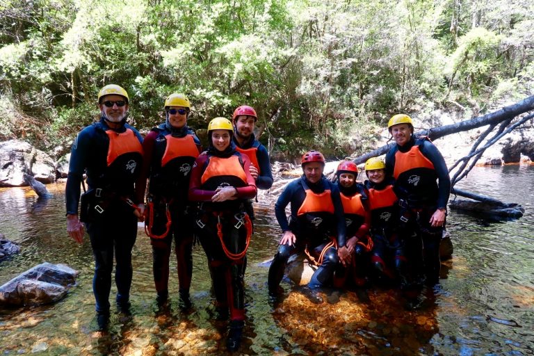 A large group of canyoneers in wetsuits pose at the bottom of Dove Canyon in Tasmania