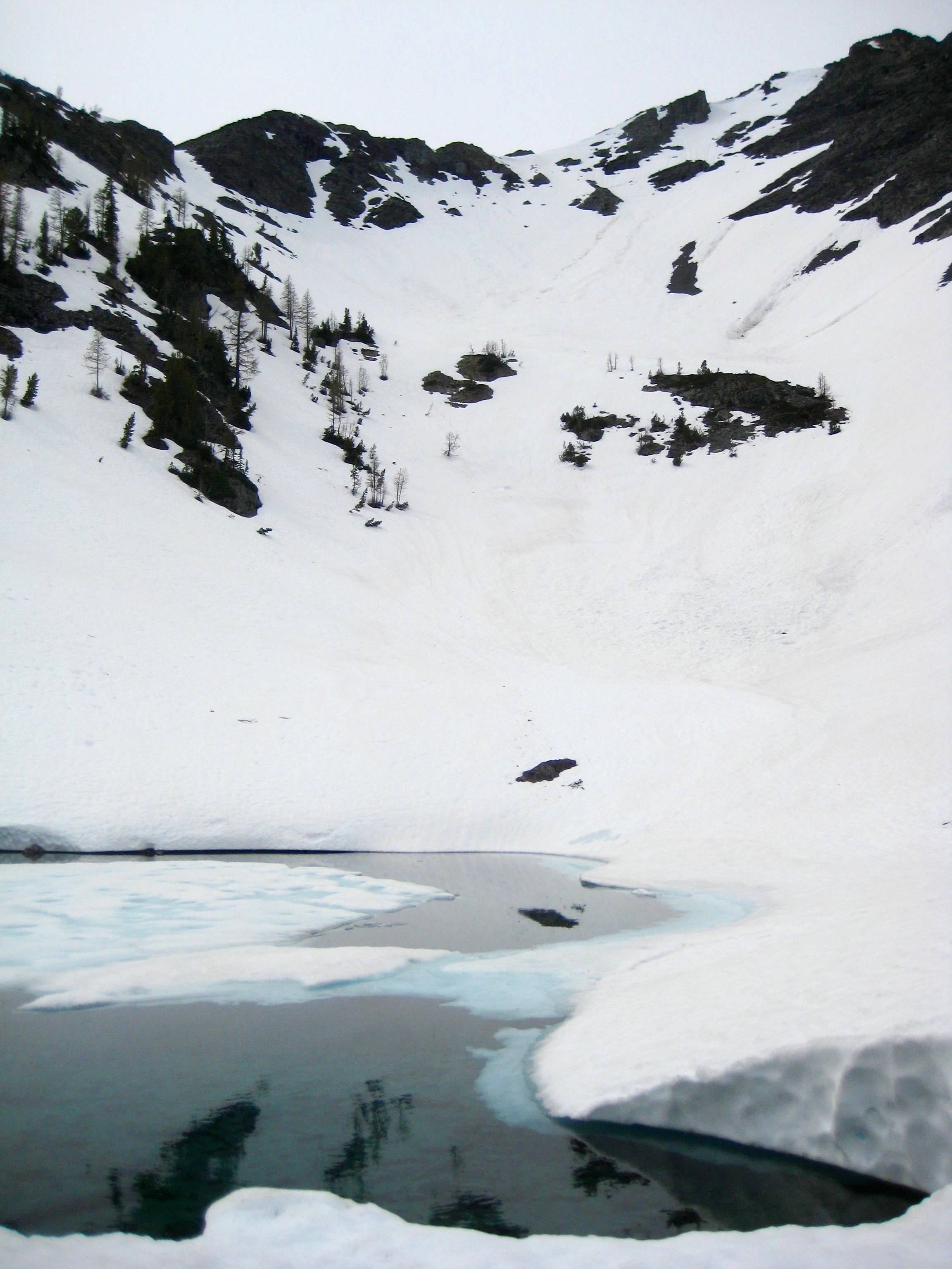snow filled basin with melting tarn below Robinson Mountain in the Pasayten Wilderness