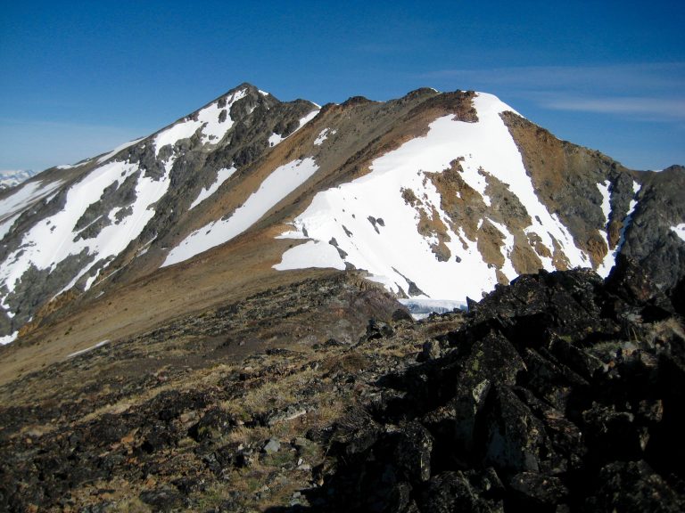 A long curving ridge with snow on one side leads to the summit of Robinson Mountain in the Pasayten Wilderness