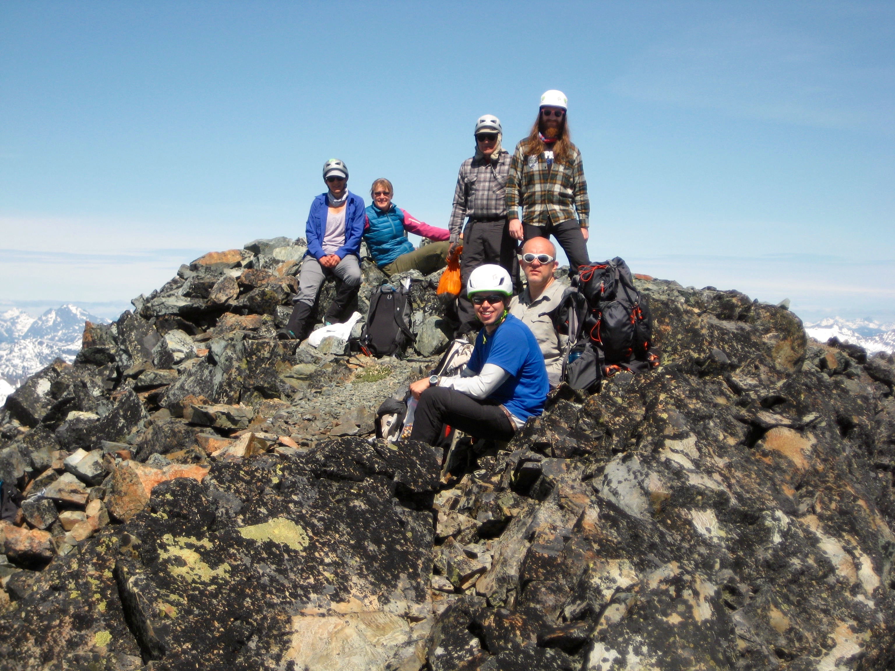 group of mountain climbers sitting and stannding on the rocky summit of Robinson Mountain in the Pasayten Wilderness