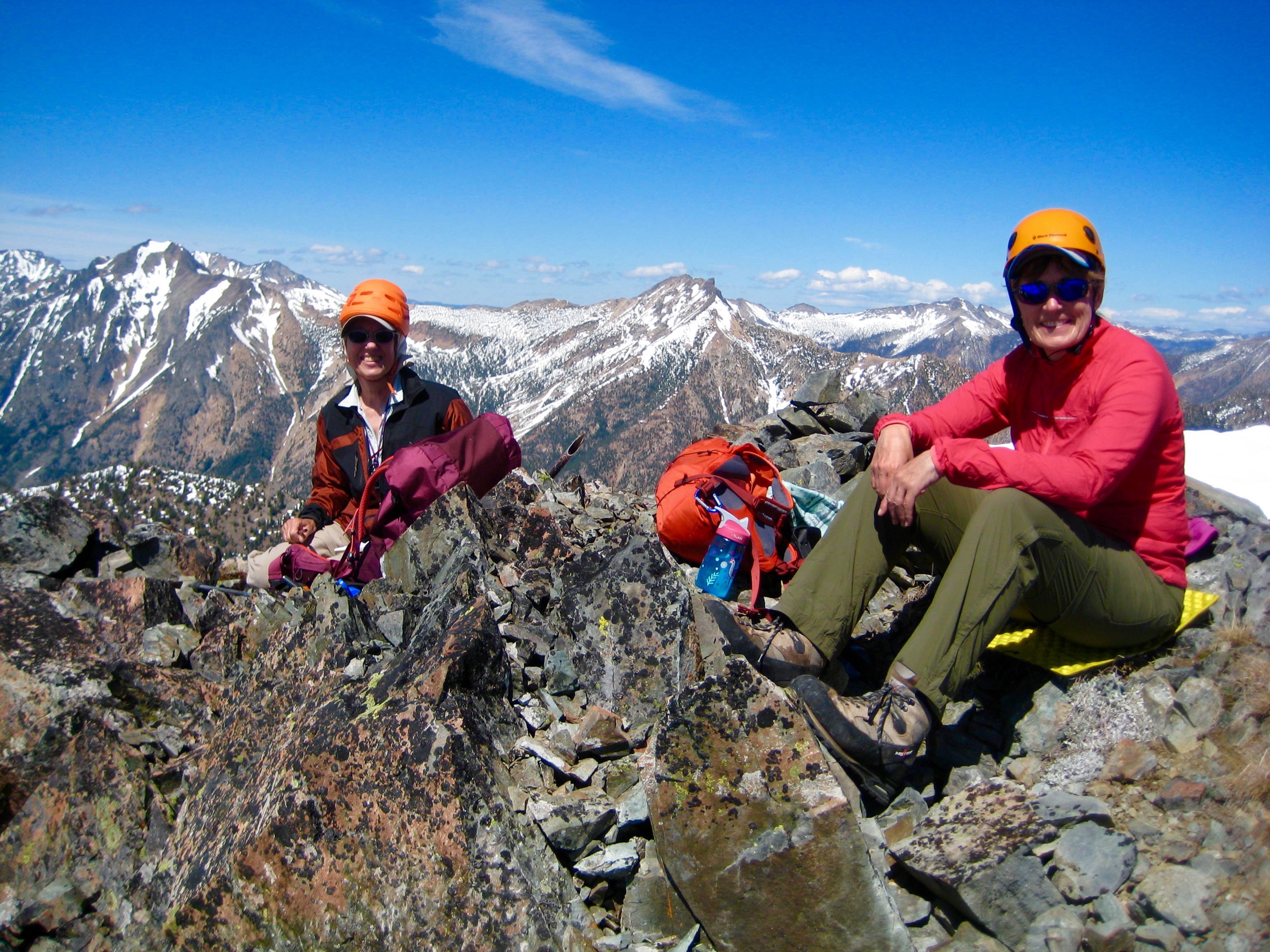 mountain climbers taking a break in the rocks on the summit of Beaity Peak with the Pasayten Mountains in the background