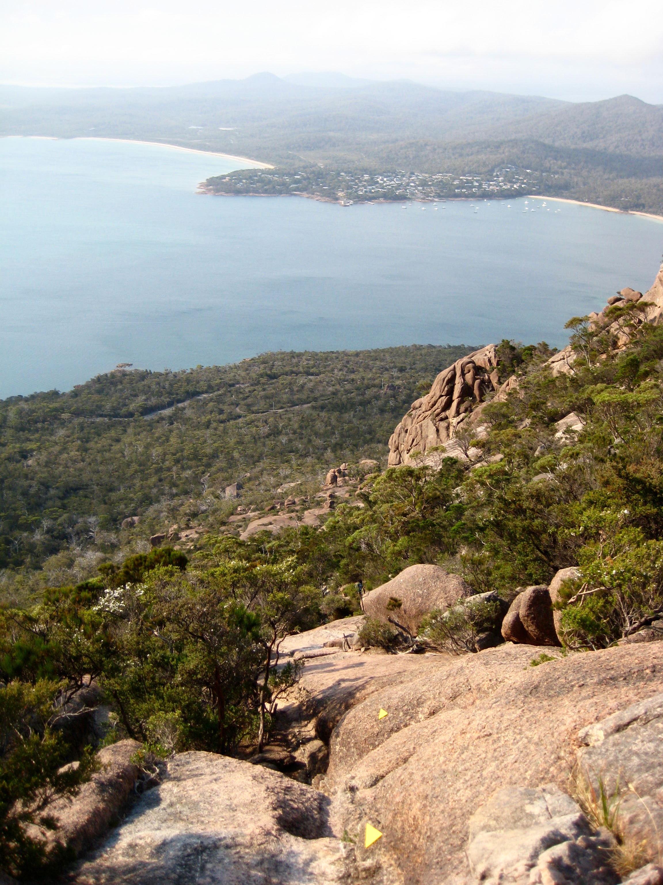 looking down on Coles Bay from the hiking route up Mt Amos in Tasmania's Freycinet National Park with rock slabs and green forests