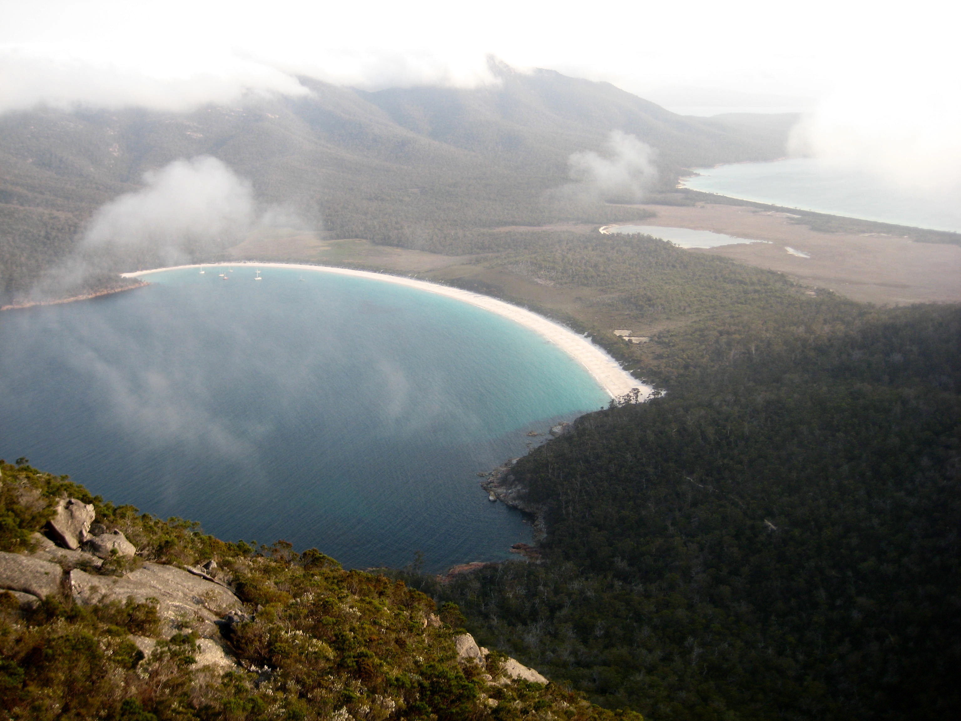 Wineglass Bay and Hazards Beach with wifting clouds as seen from the summit of Mt Amos in Tasmania's Freycinet National Park