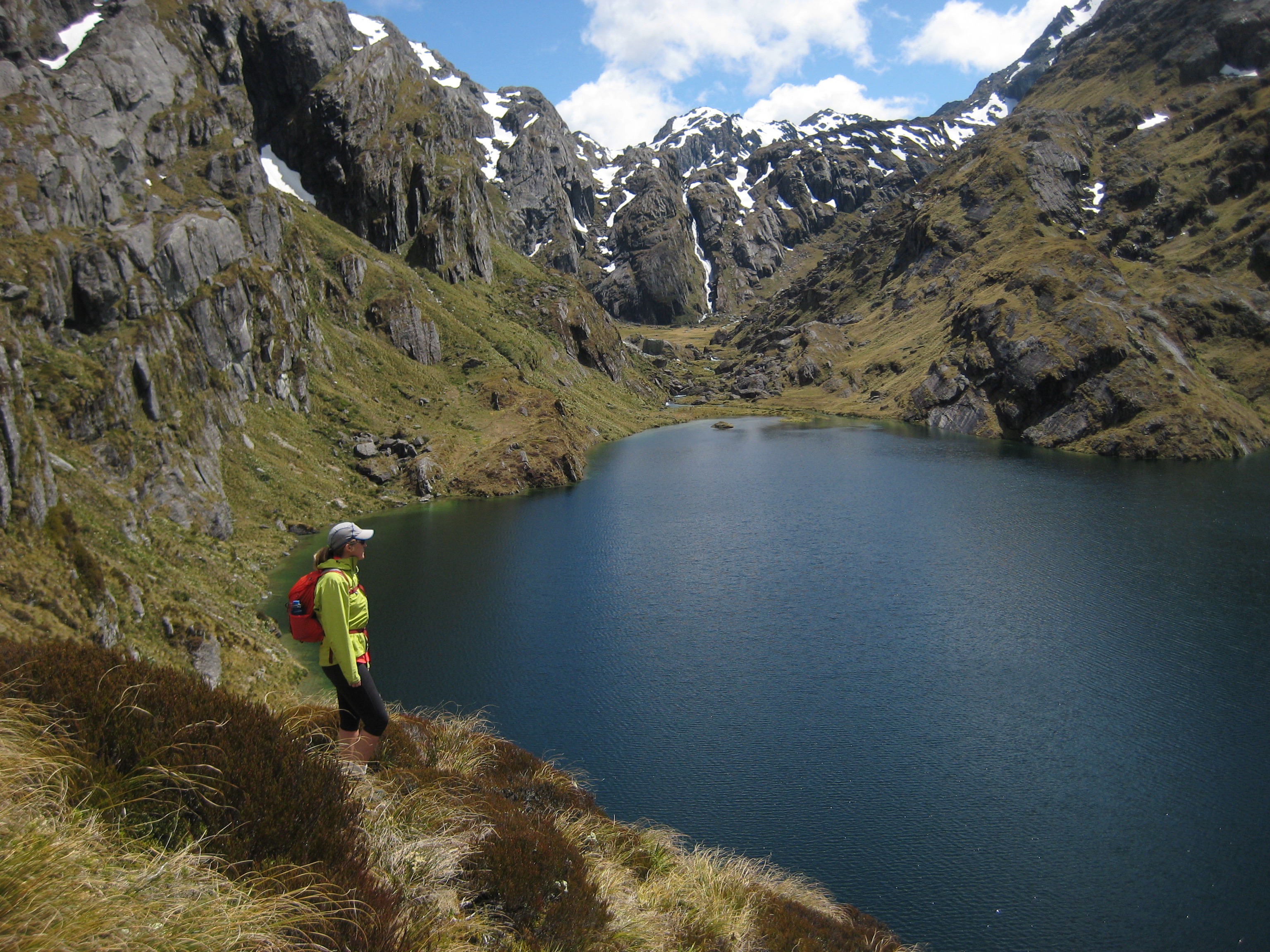 A hiker looks across Lake Harris below Conical Hill on the Routeburn Track