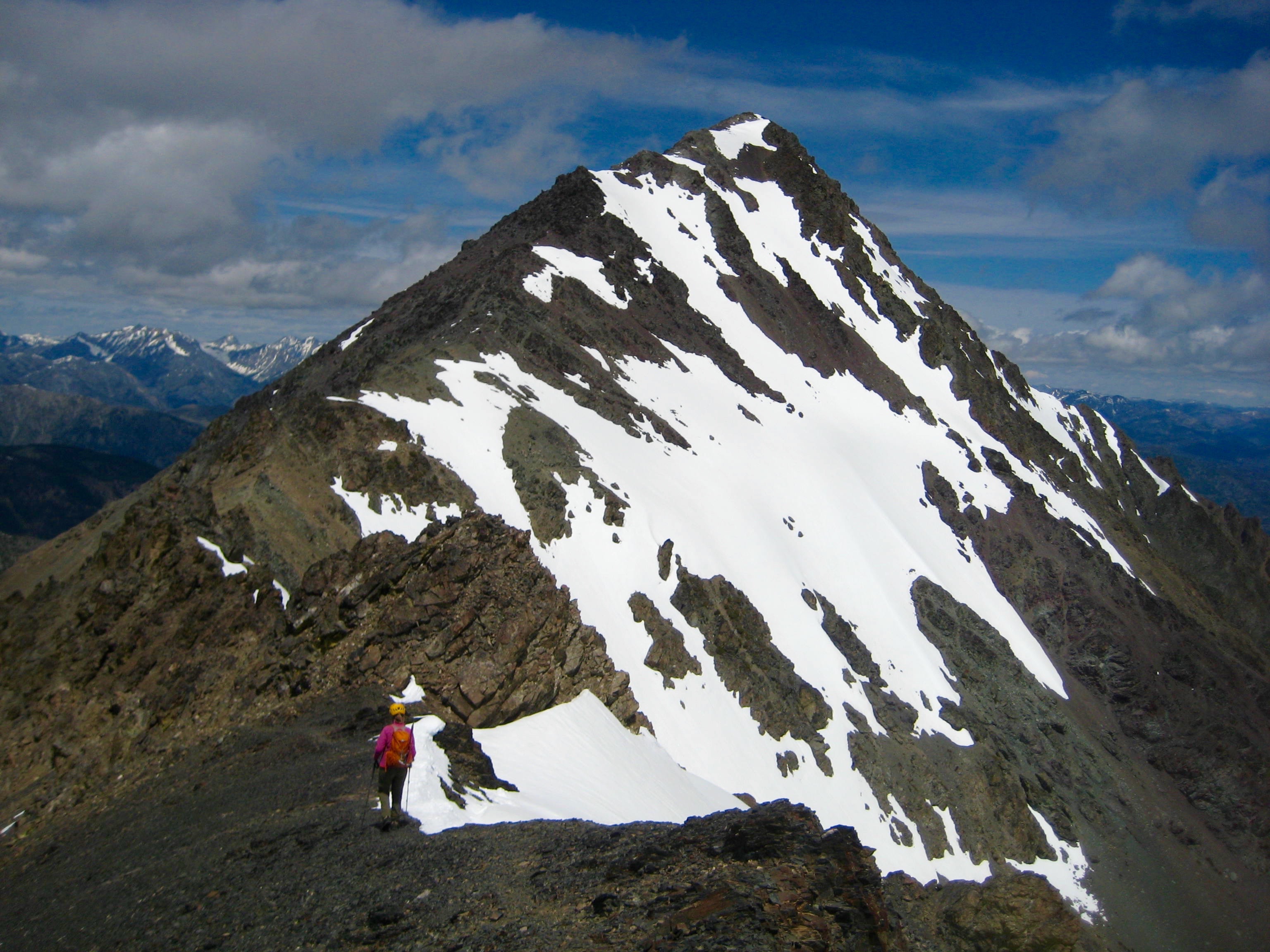 A mountain climber walks along a narrow ridge leading to North Gardner Mountain