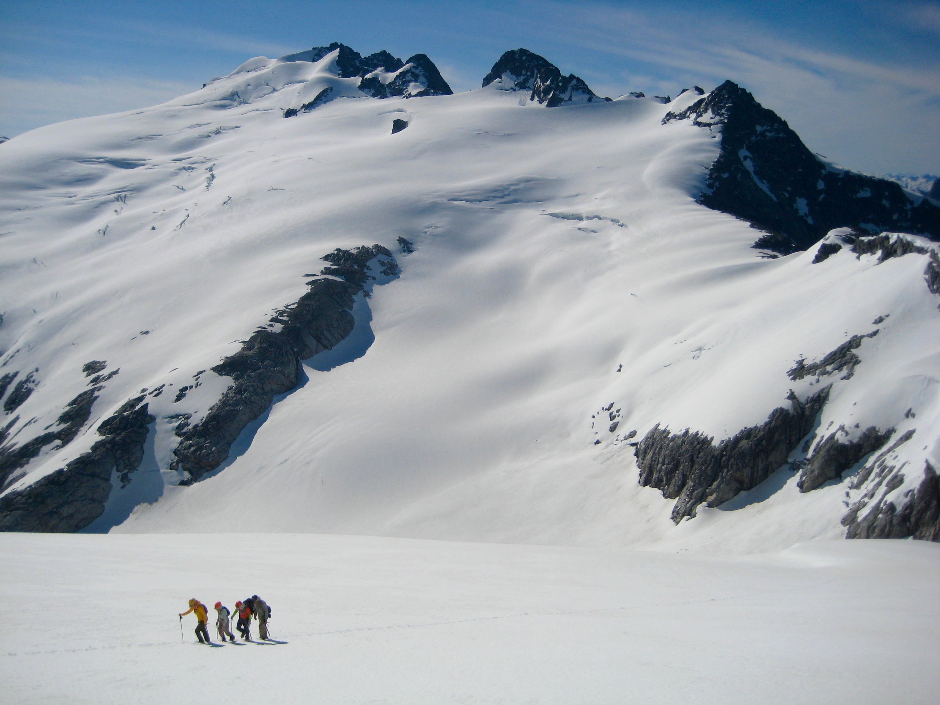 climber booting up the snow heading toward Whatcom Peak with Mt Challenger in the background