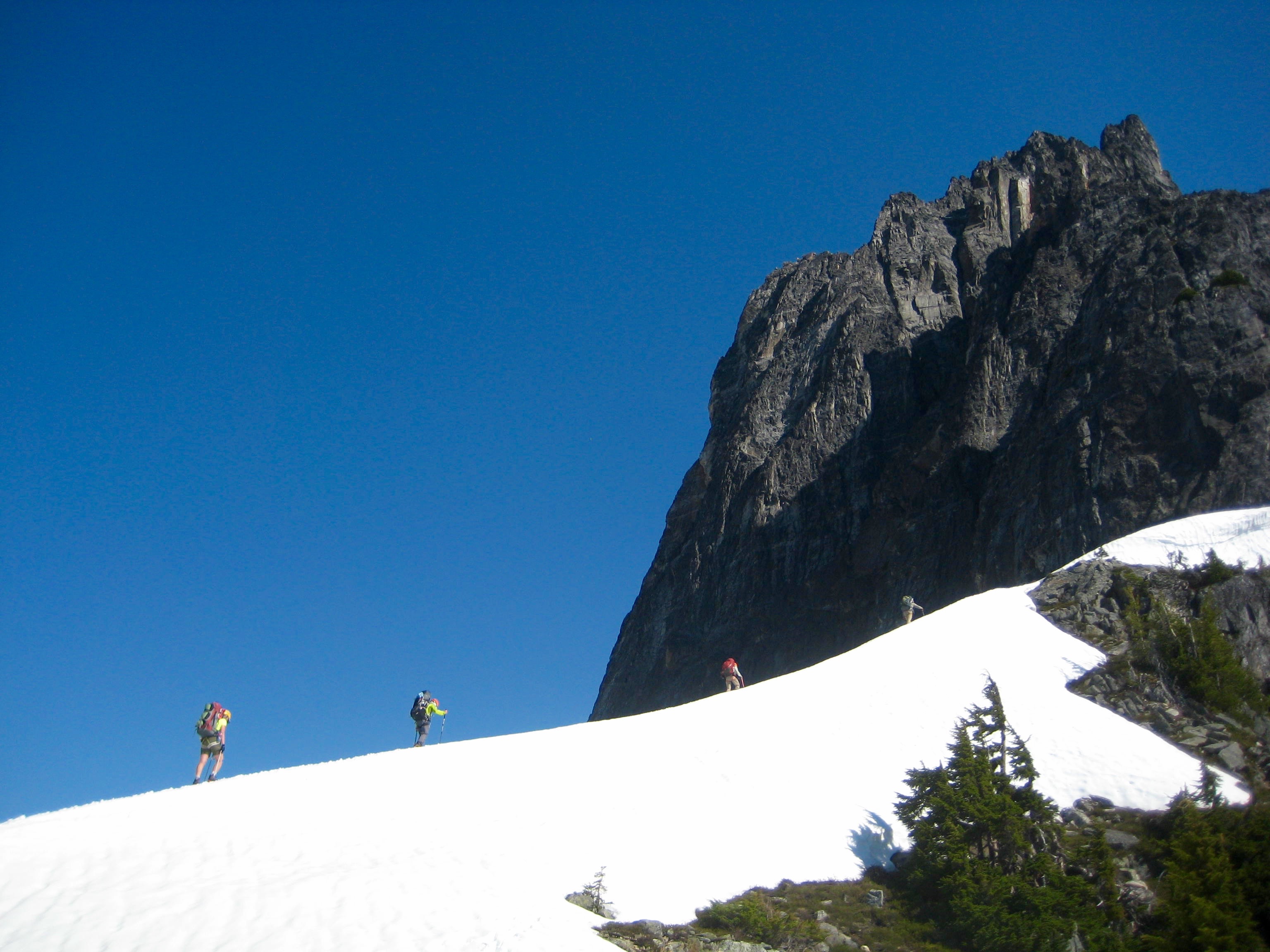 Climbers booting up ridge line heading out of camp at Pickell Pass