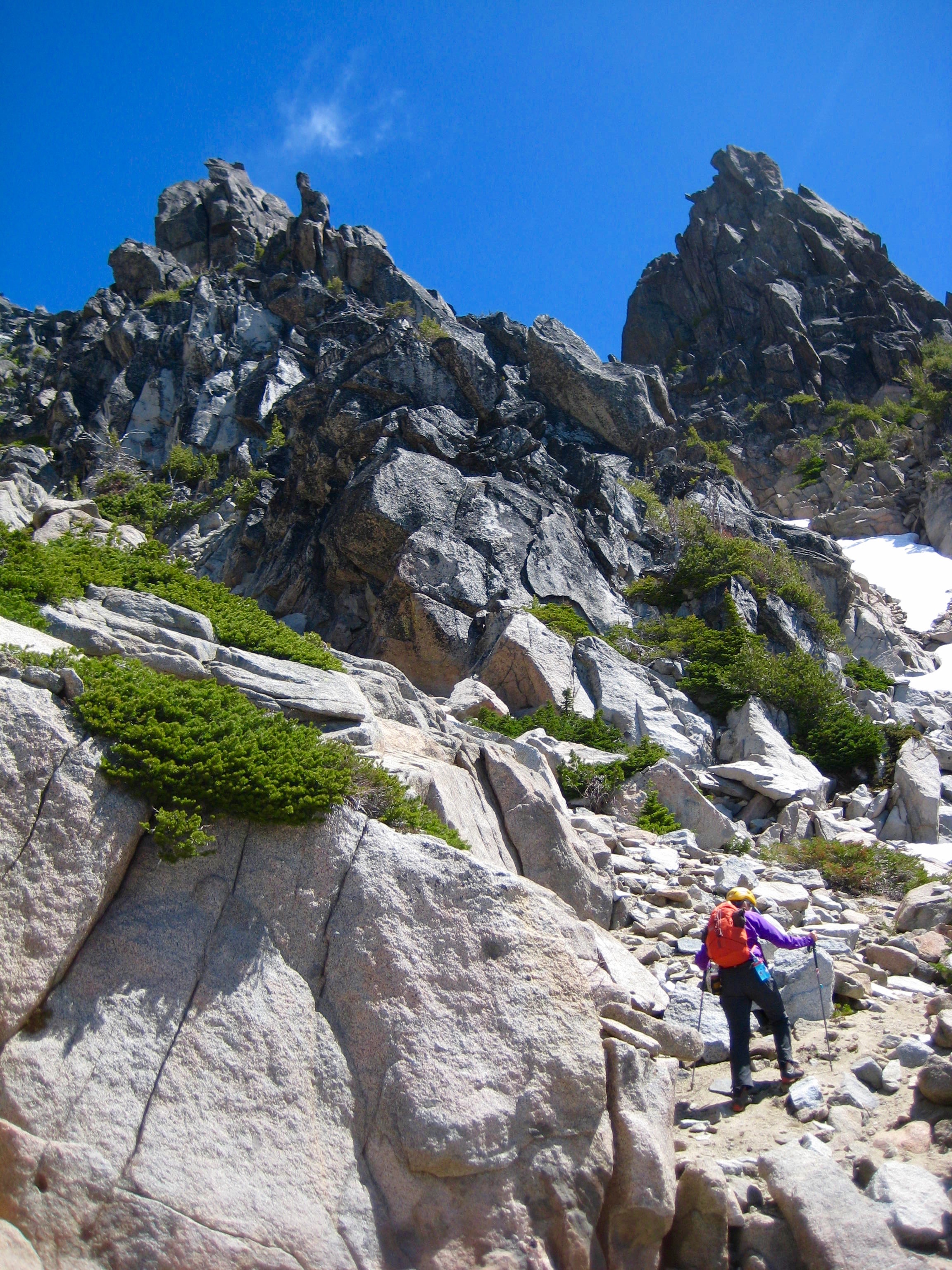 mountain climber crossing scree field under rock horns on Sherpa Peak in the Icicle Mountains
