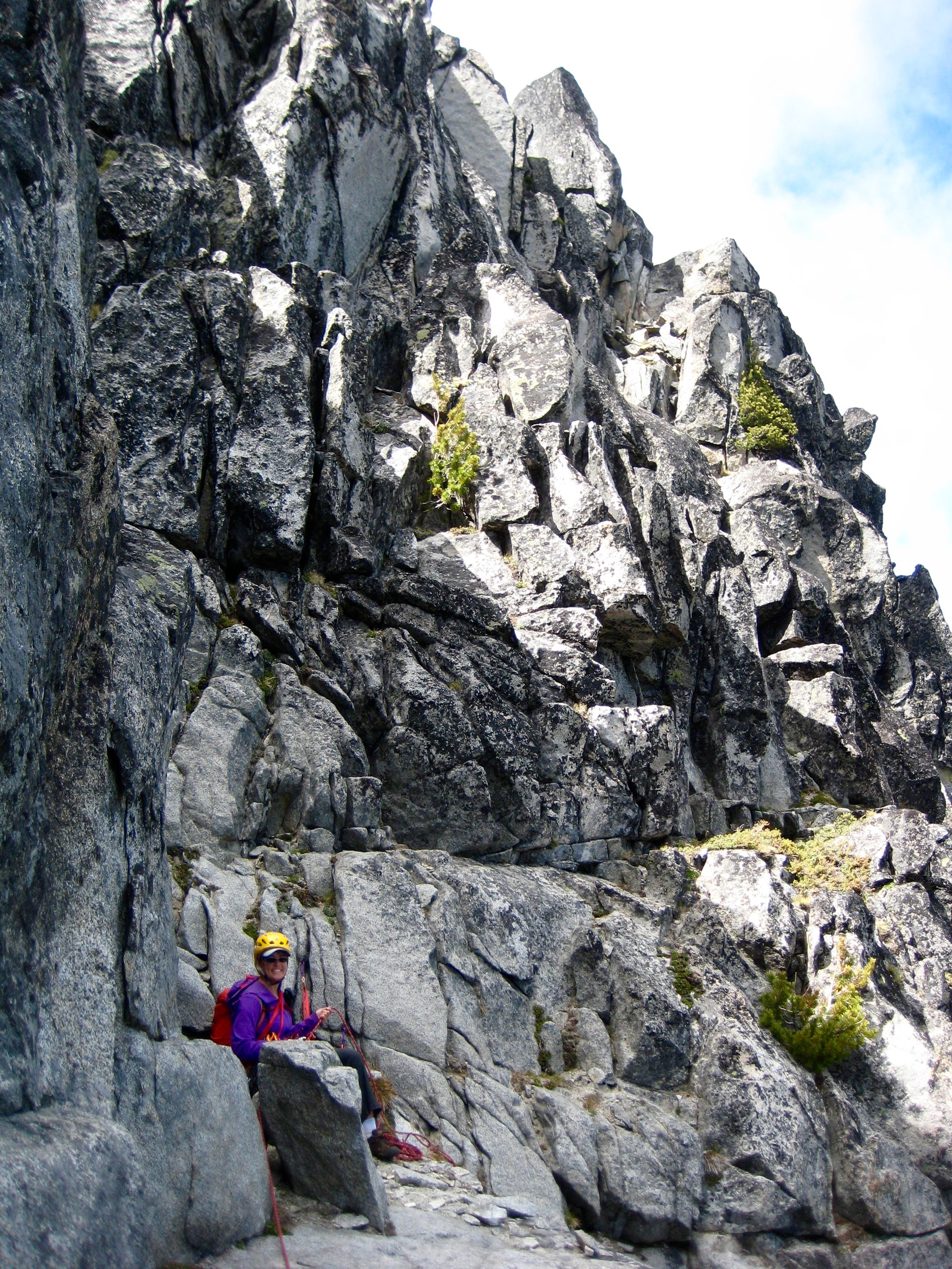 mountain climber belaying from rock ledge of the steep rock shoulder of Sherpa Peak in the Icicle Mountains
