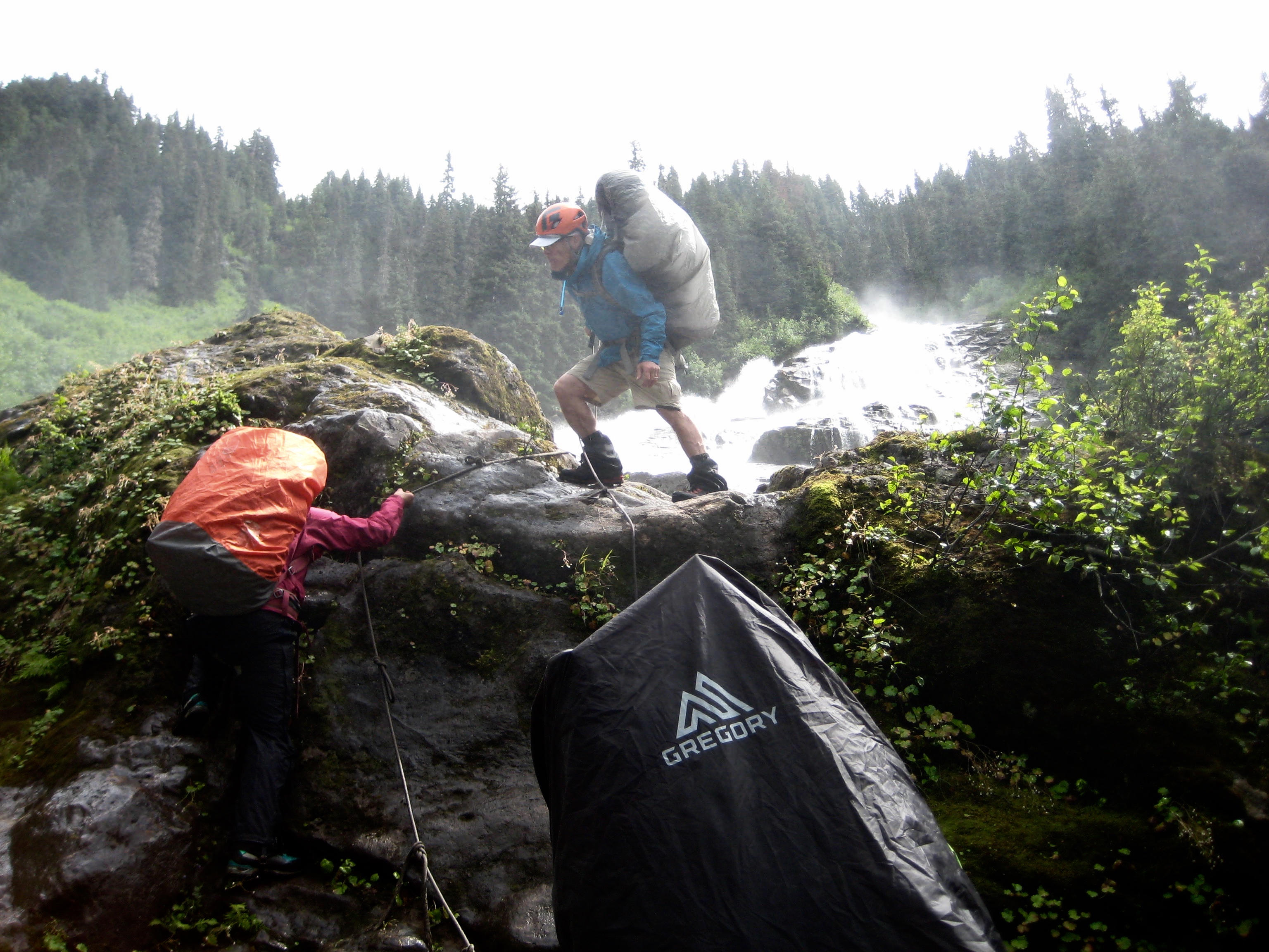 mountain climbers ascending wet boulders at the base of Depot Creek Falls in the American Chilliwack Mountains