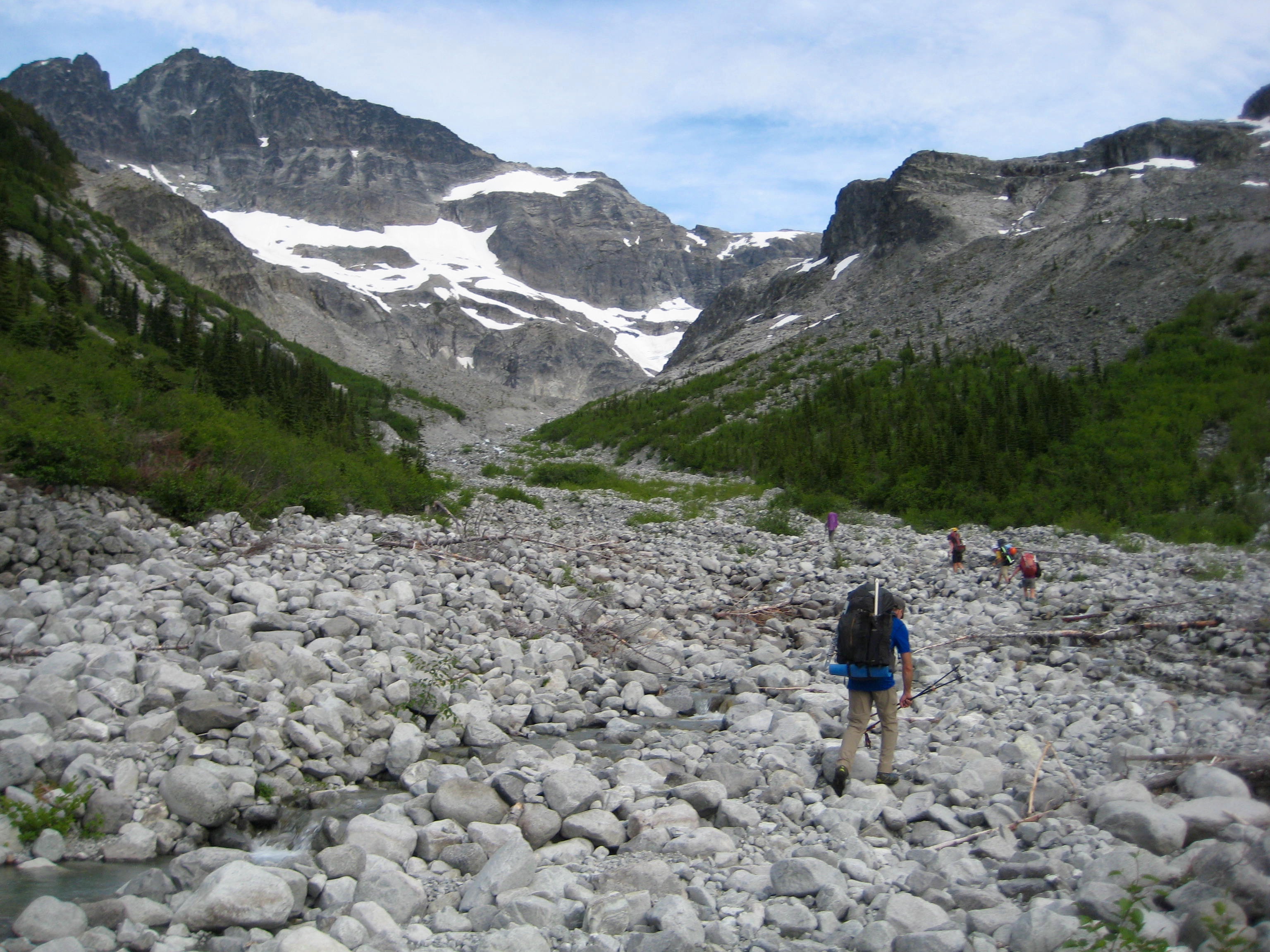 Mountain climbers ascending boulder field with Easy Mox in the American Chilliwack Mountains in the background
