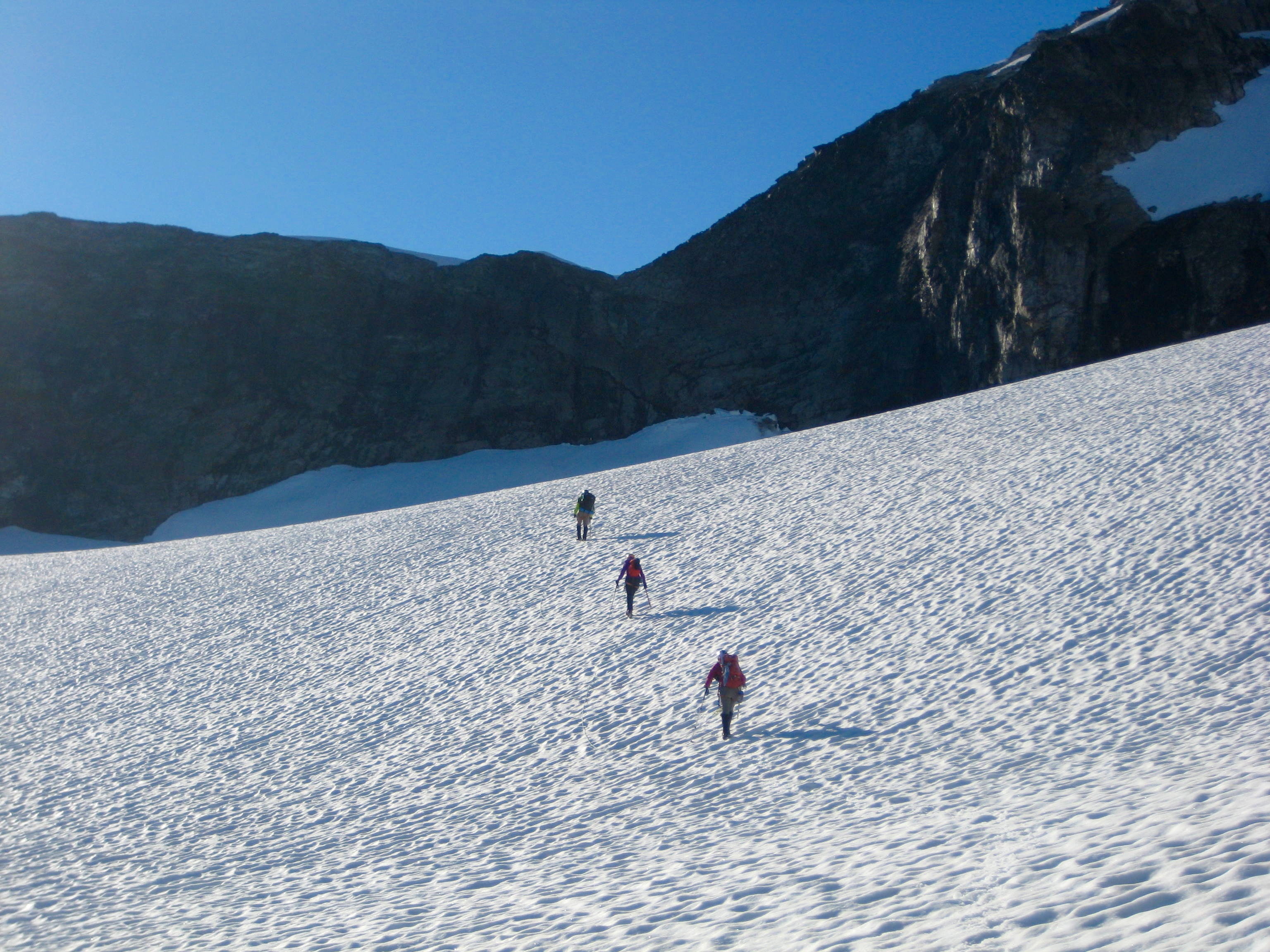 roped team of mountain climbers crossin gthe Redoubt Glacier  with the NE Ridge of Easy Mox Peak in the American Chilliwack Mountains in the distance