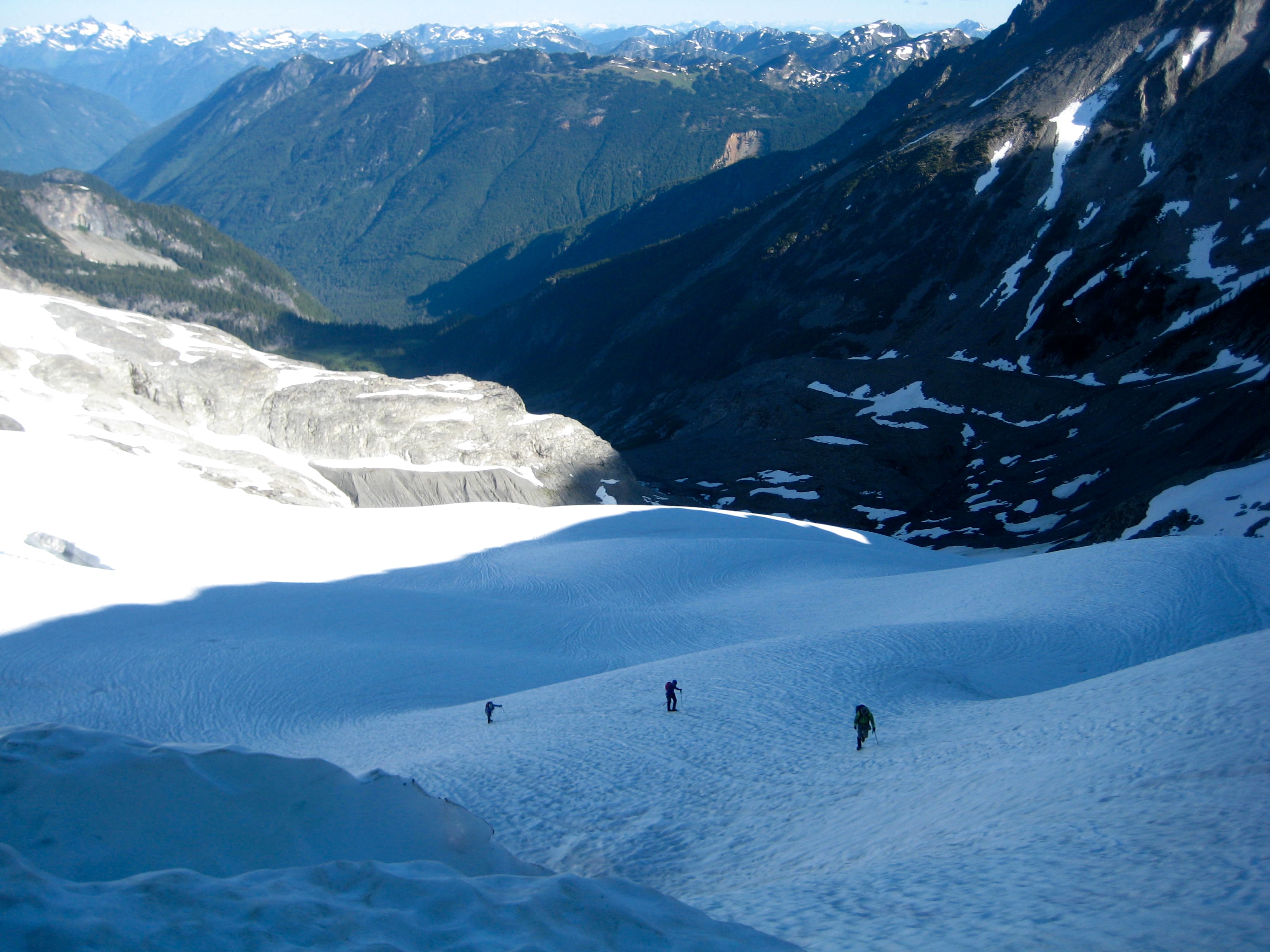 Roped mountain climbing team high on Redoubt Glacier with valley floor in background