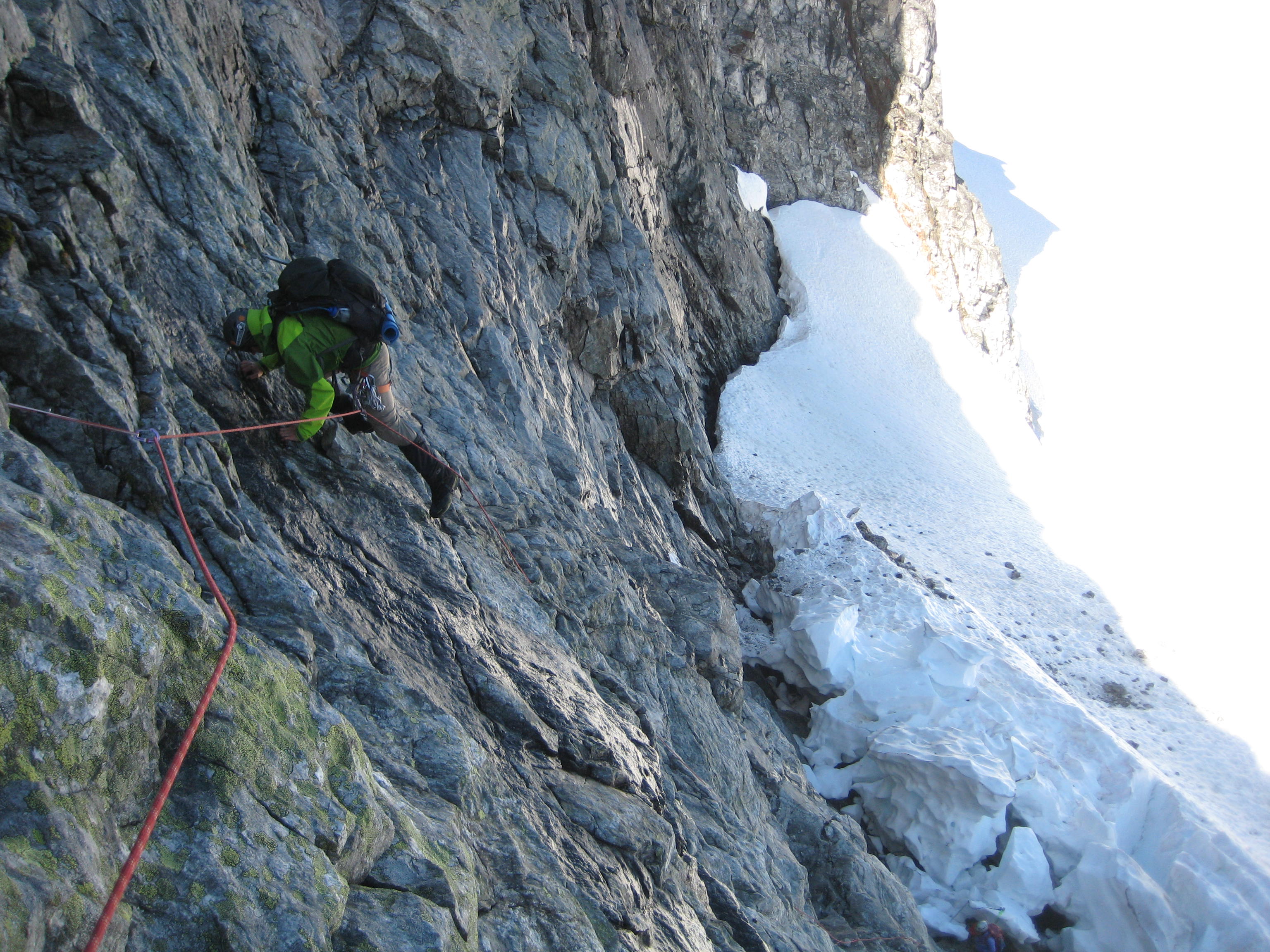 roped mountain climber scrambling steep rock face of the NE ridge of Easy Mox Peak in the American Chilliwack Mountains