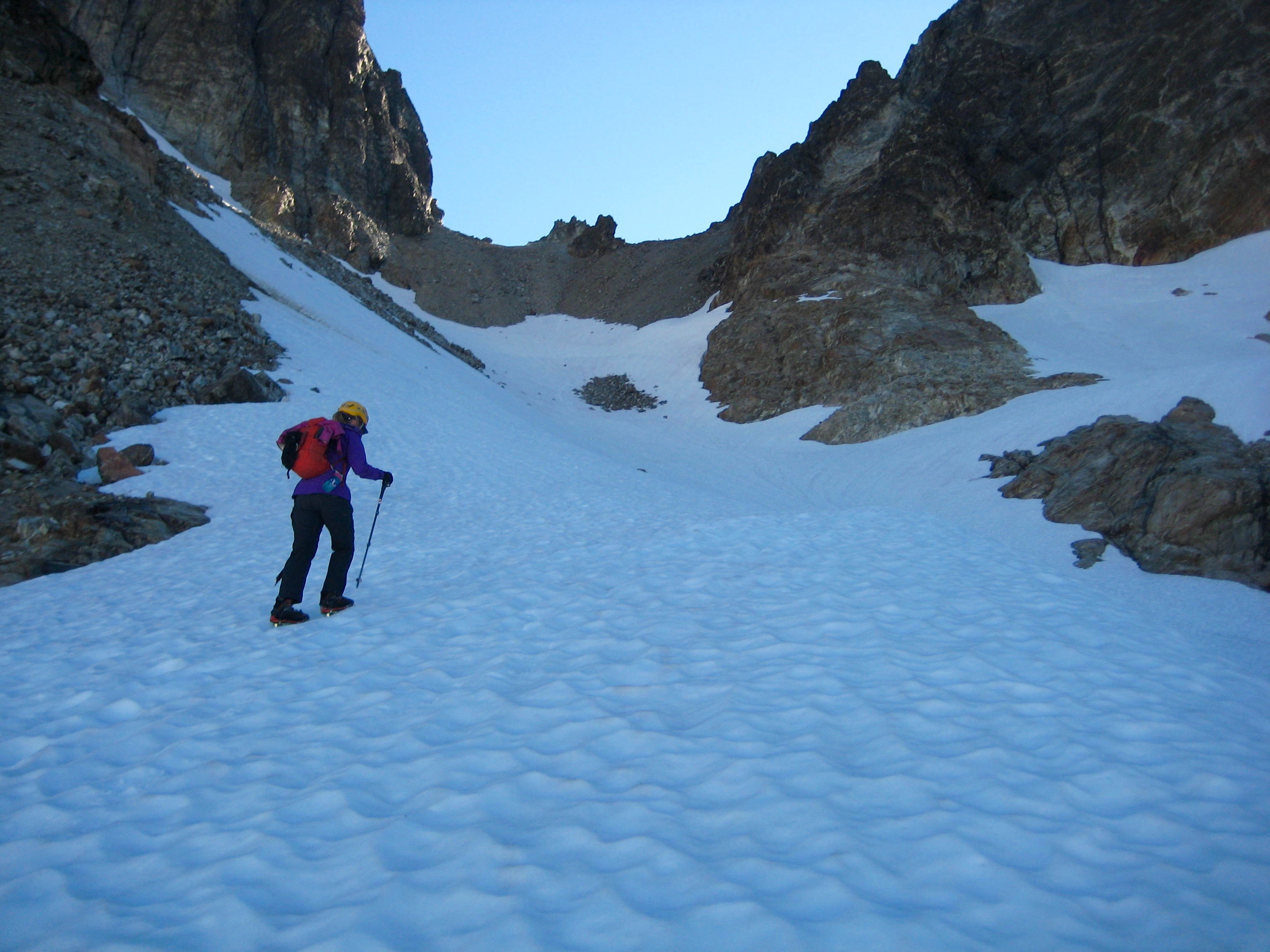 mountain climber booting up snow field with baren Col Of The Wild in the American Chilliwack Mountains above