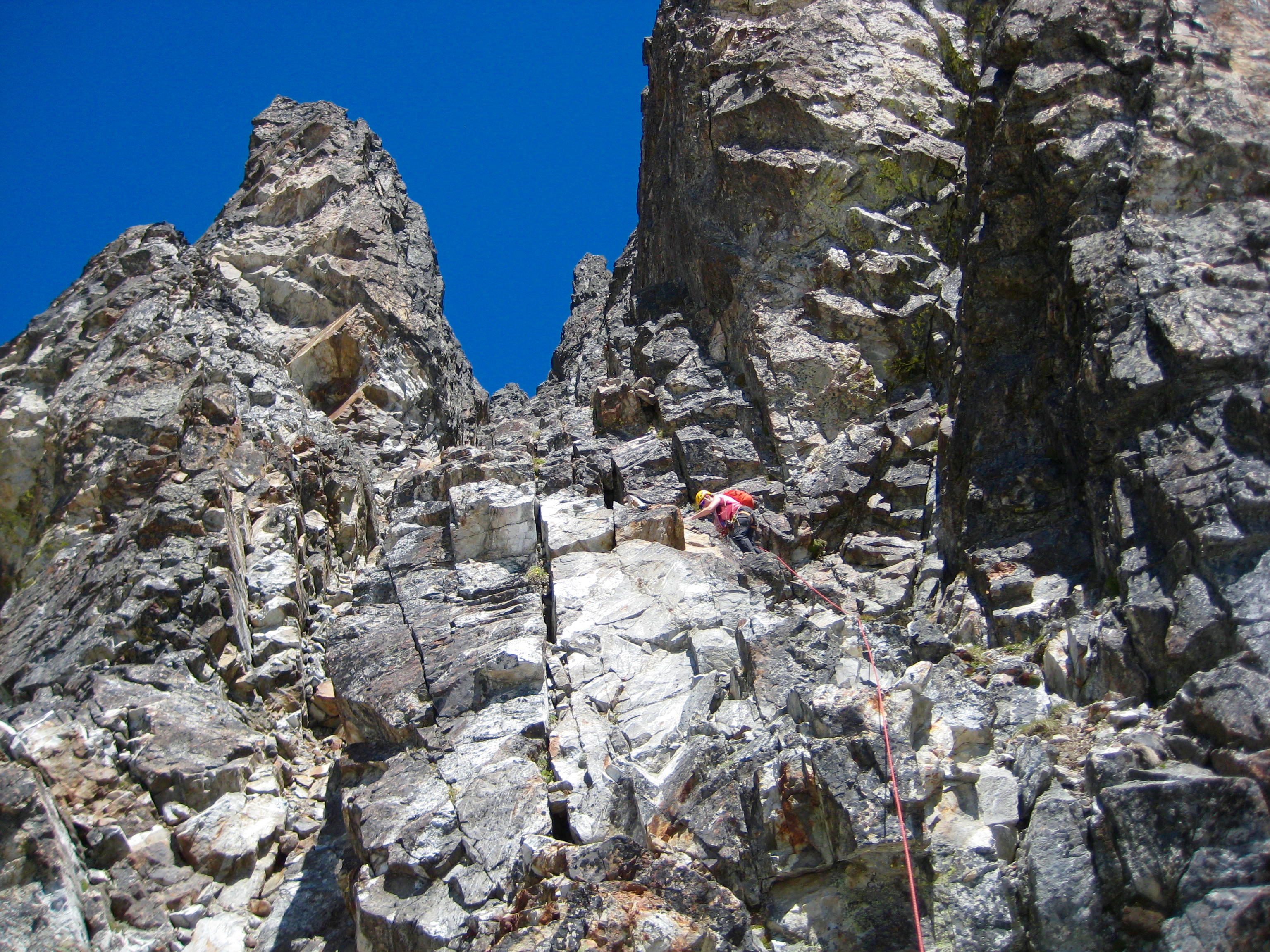 Mountain Climber scrambling up to the high notch below the summit rock of Hard Mox Peaks