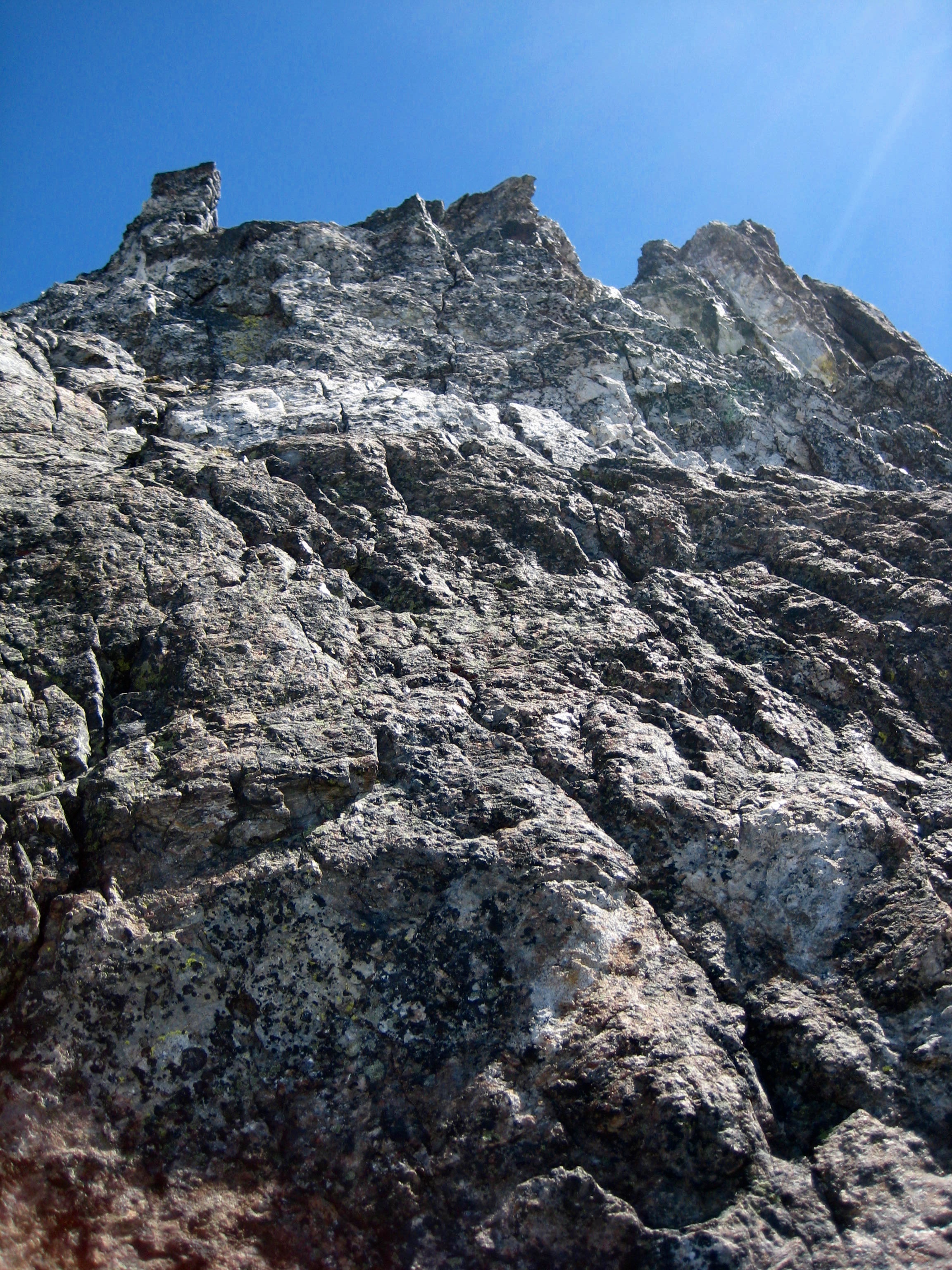 looking up steep rock at summit tower of Hard Mox Peak in the American Chilliwack Mountains 