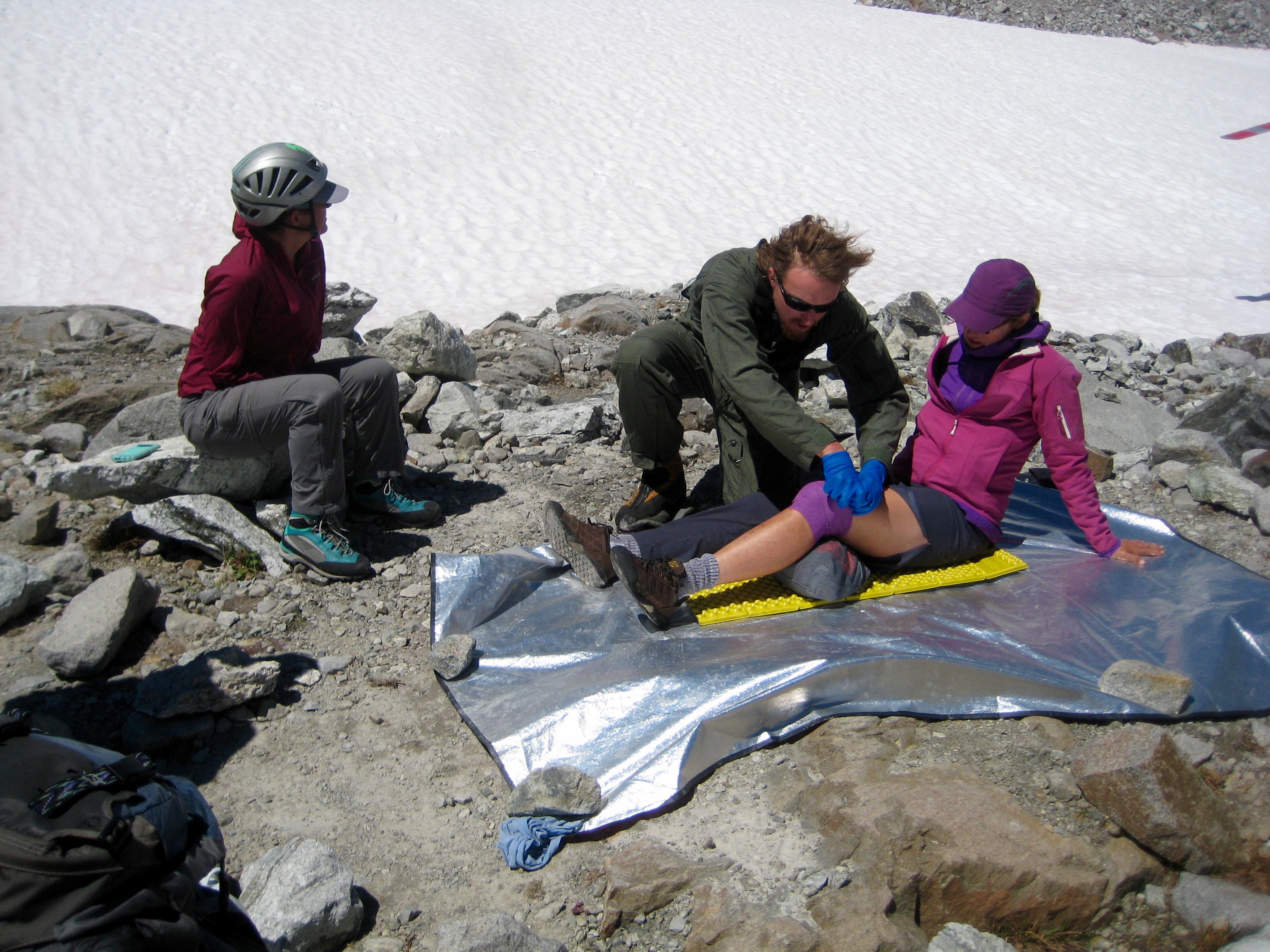 injured mountain climber with mountain rescue ranger on rock slab next to Redoubt Glacier in the American Chilliwack Mountains