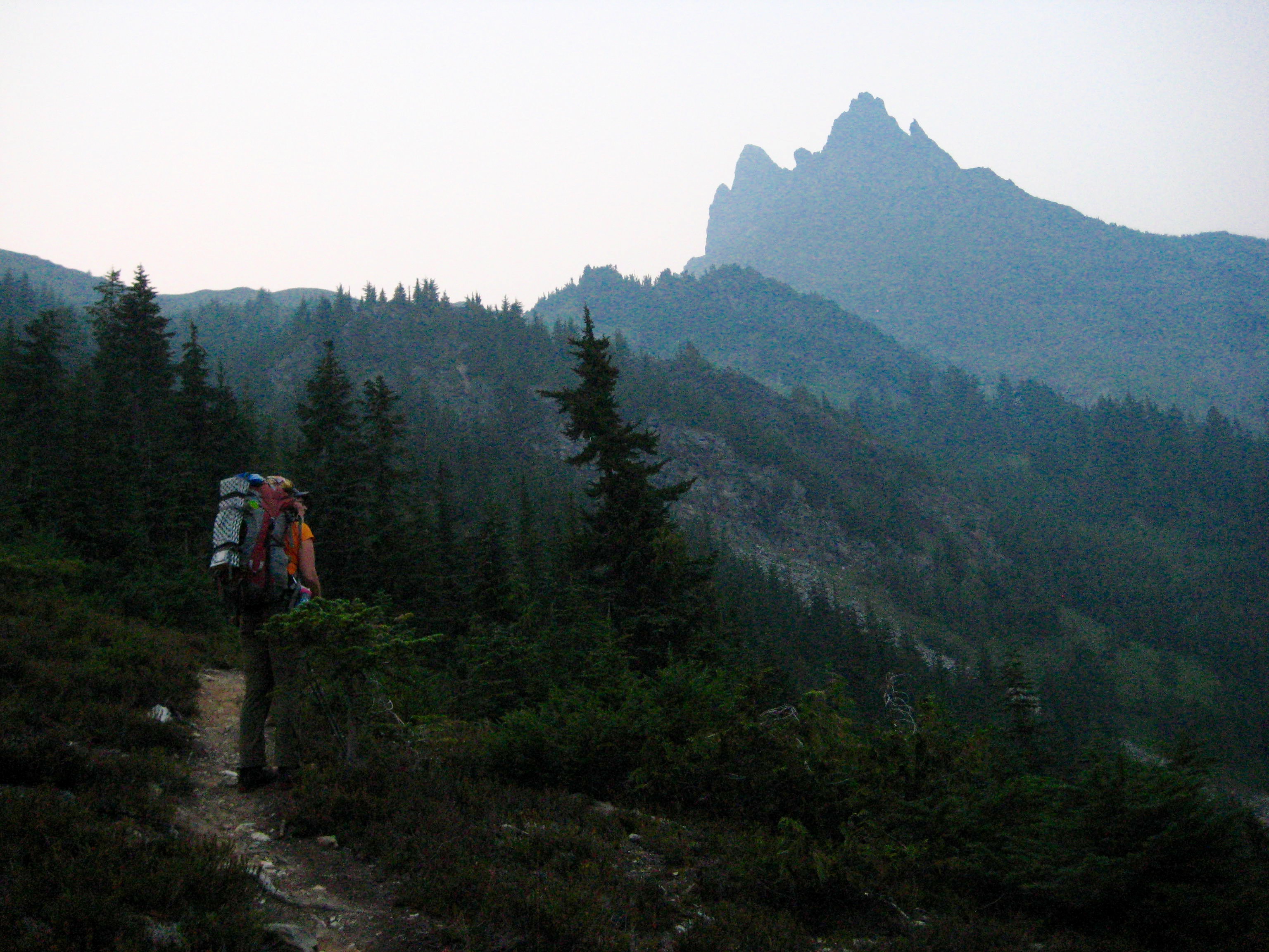 mountain climber standing on climber's path in the evening light looking at Baby Munday Peak in the Cheam Range