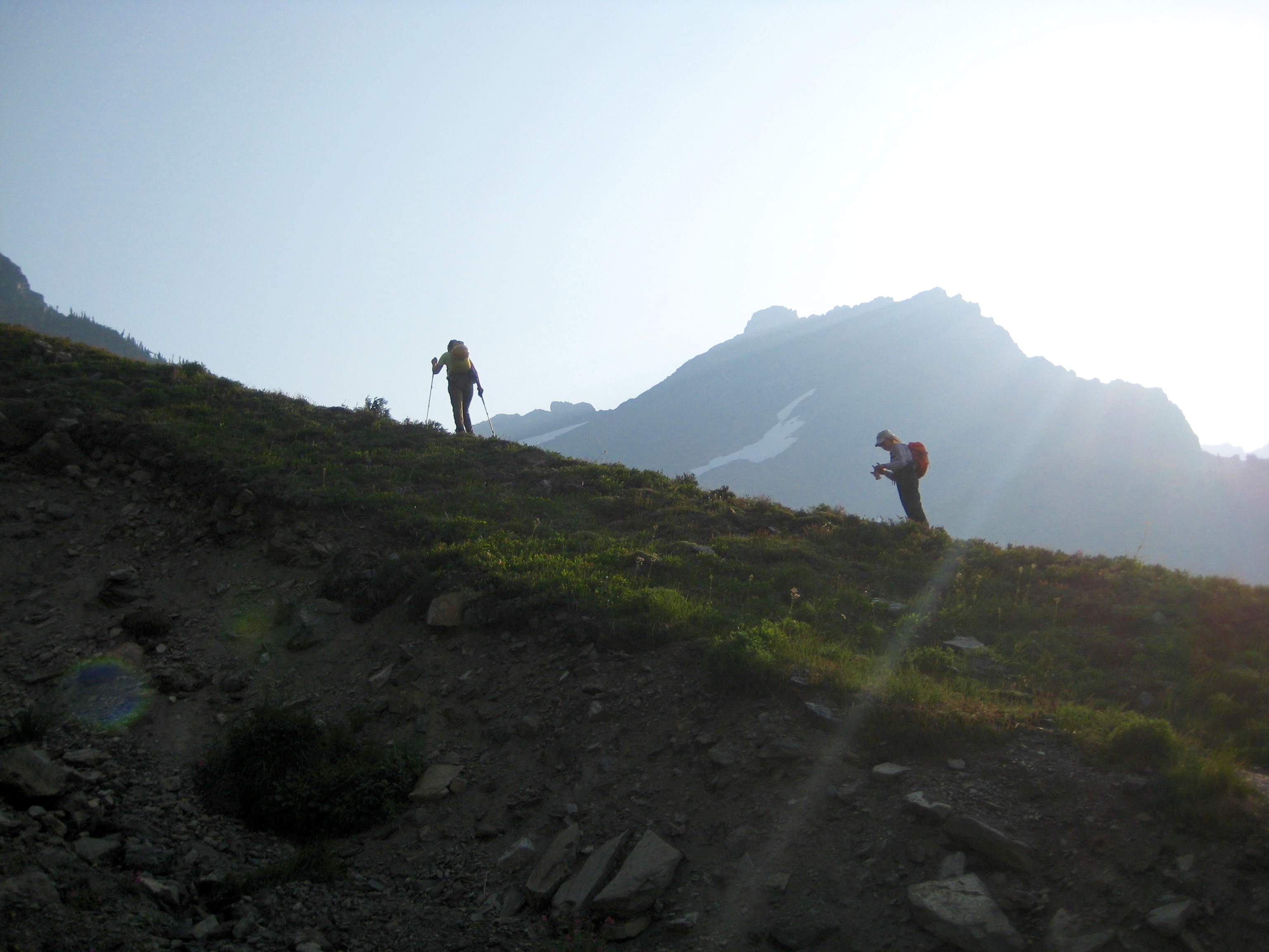 Climbers scrambling on the horizon hiking up grass slopes toward Baby Munday Lake in Cheam Range