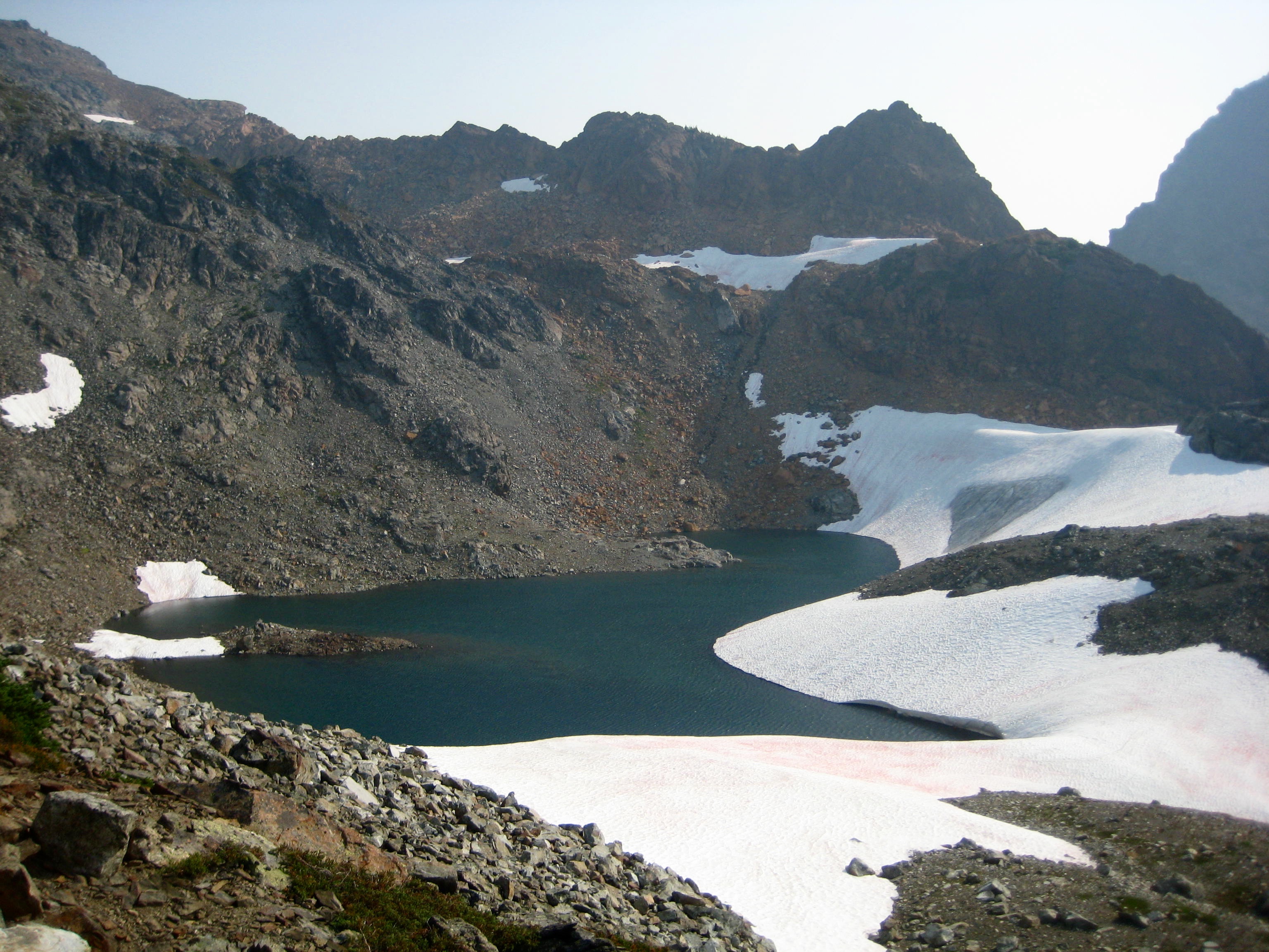 Baby Munday Lake in the Cheam Range with large snow patches and steep rock banks