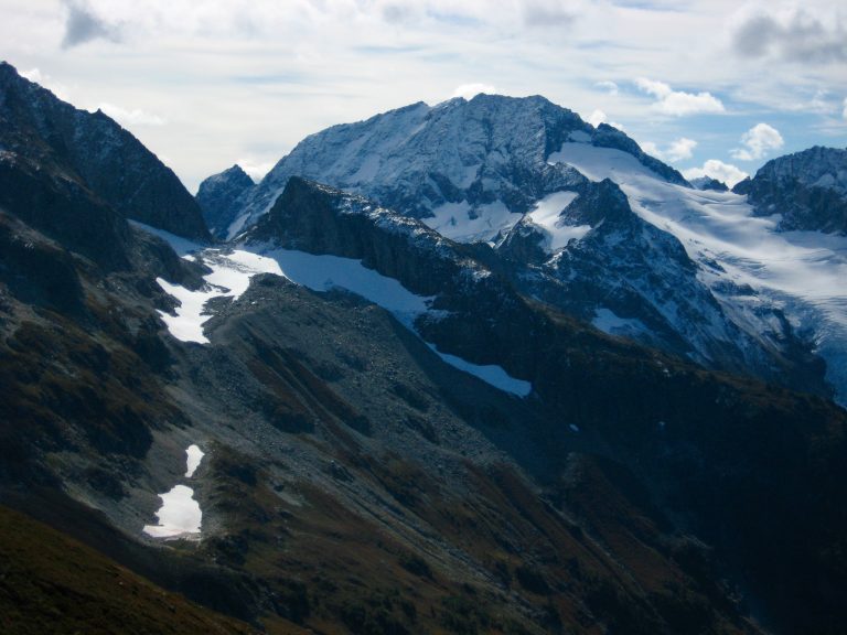 Spider Mountain with Kool-Aid Lake with mountain terrain and linguring snow patches as seen from Cache Col