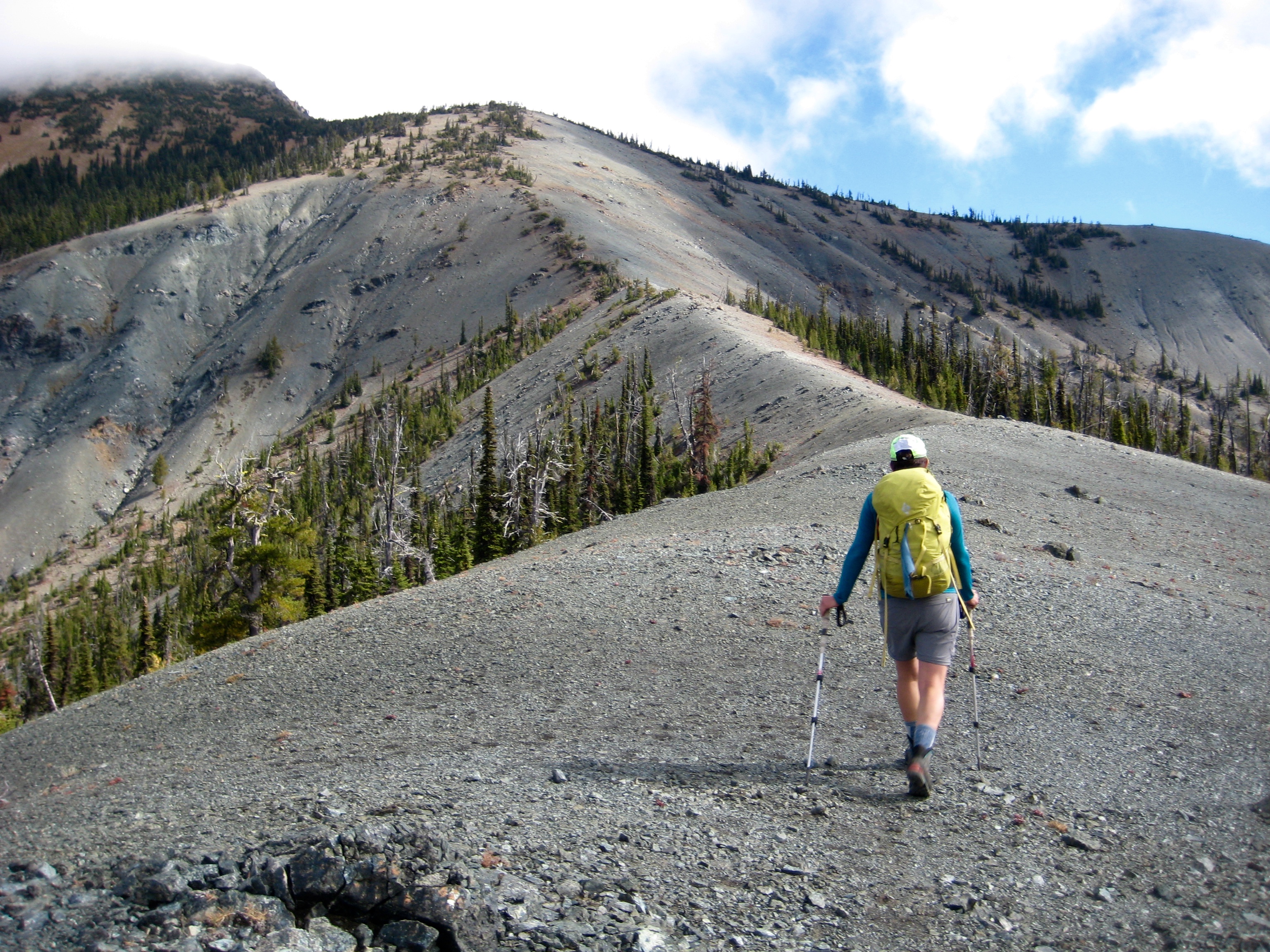 A hiker strolls up a broad smooth ridge heading toward Hawkins Mountain in the Cle Elum Mountains