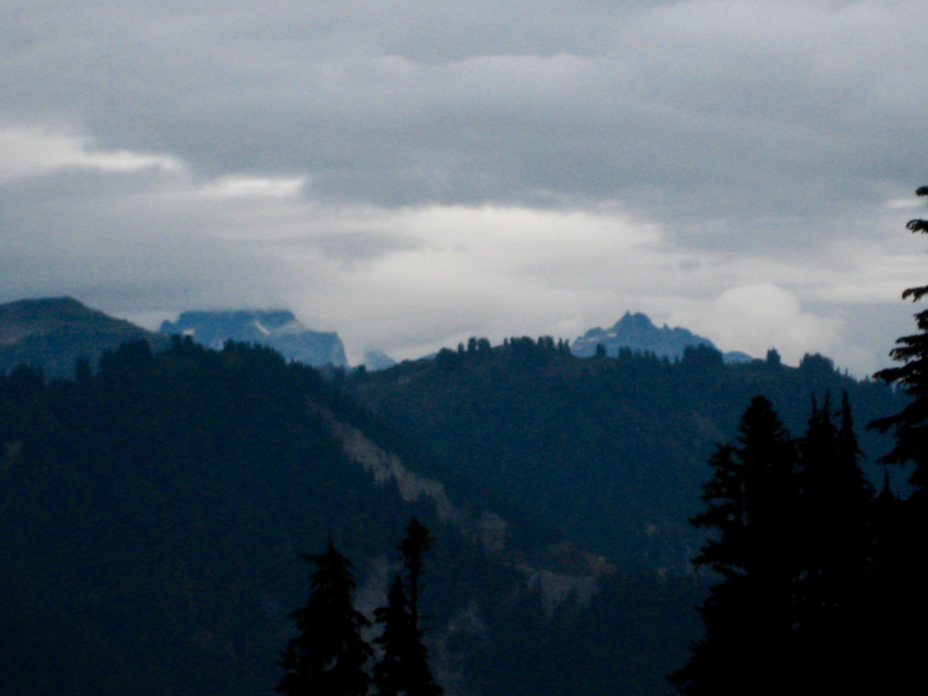 Mt Redoubt and Bear Mountain in the American Chilliwack Mountains sit above nearby ridge with storm clouds above