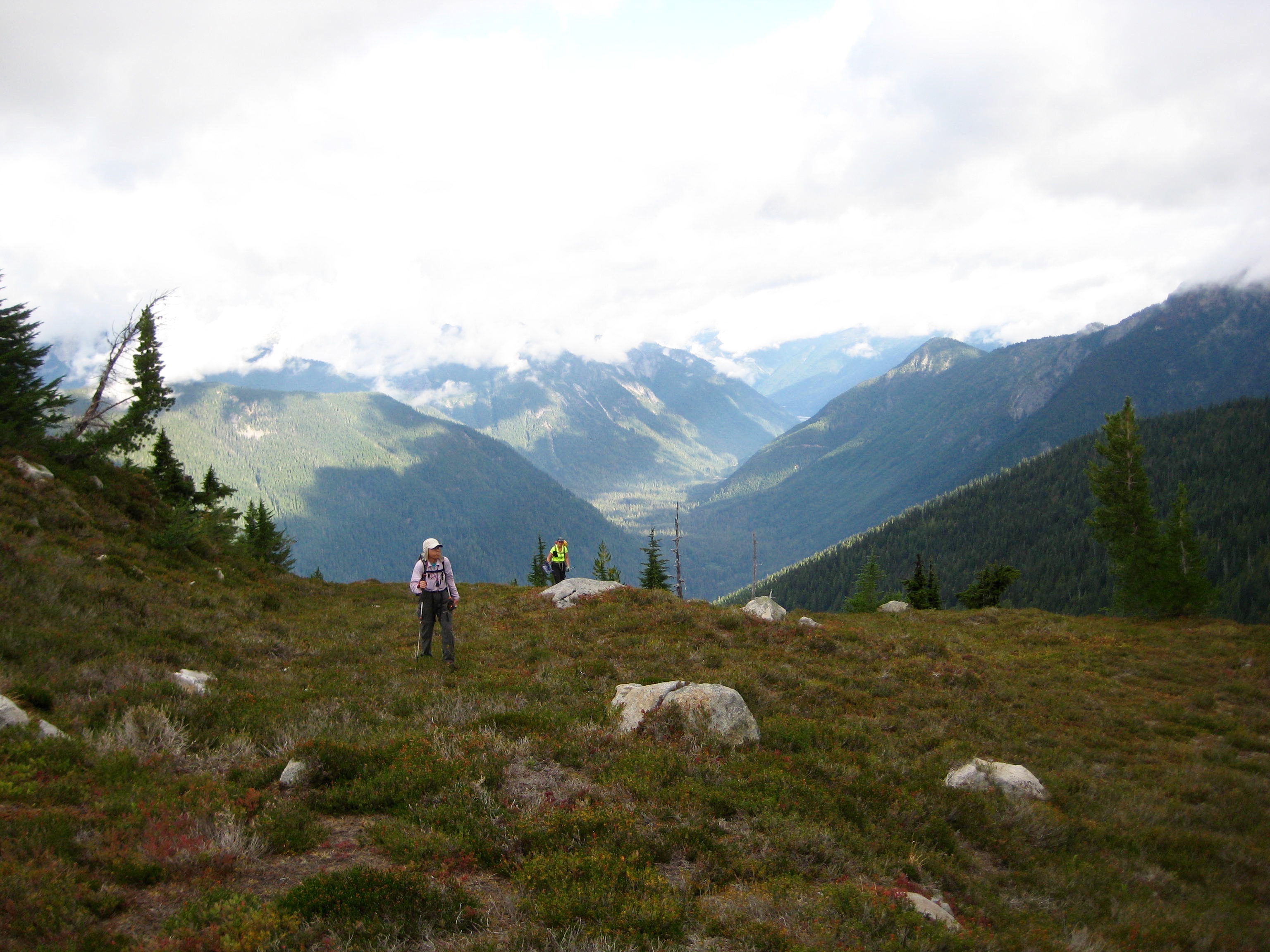 mountain climbers hiking through grassy basin with granite boulders on the ridge of Bear Mountain in North Cascades National Park